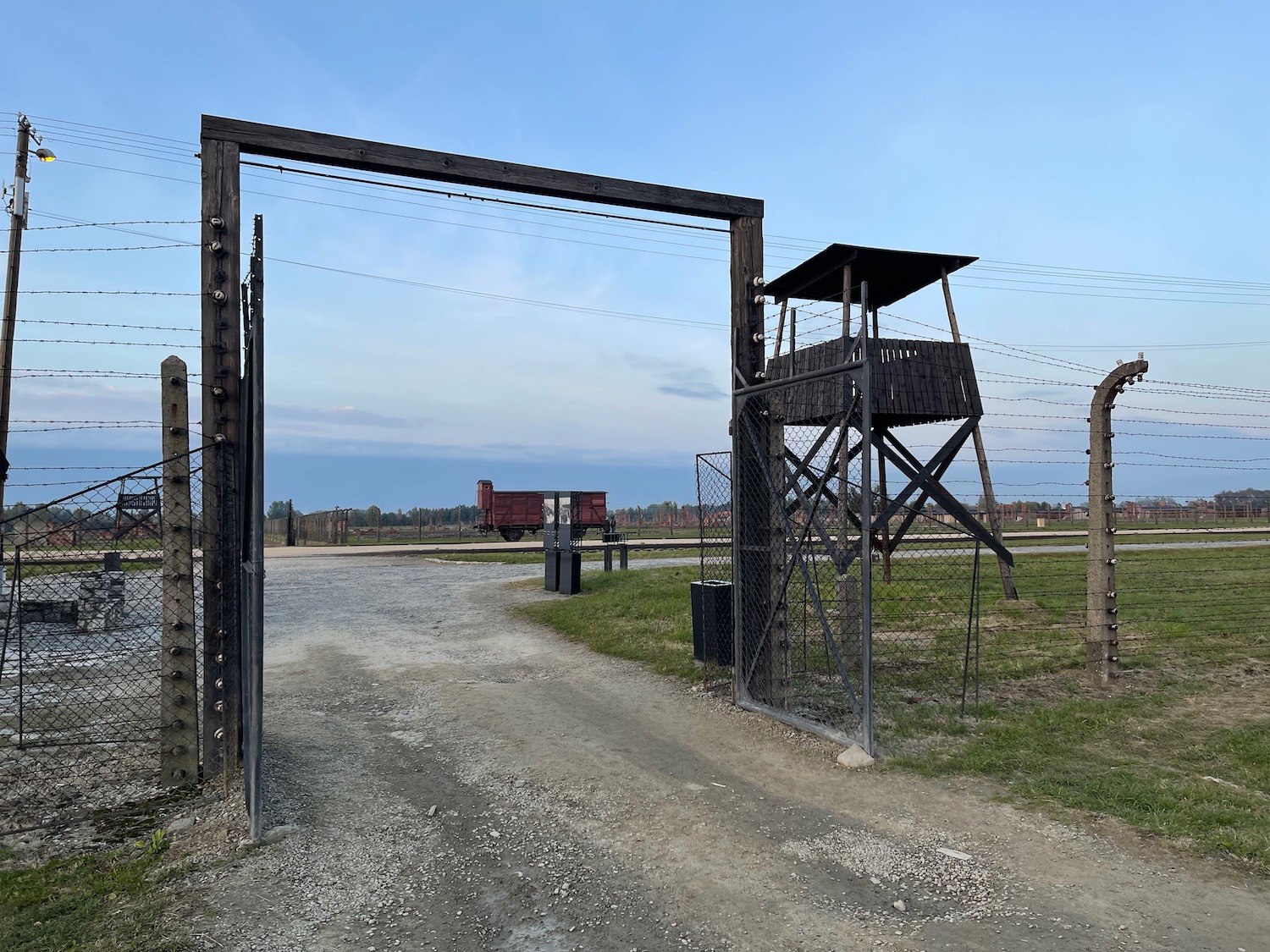 a fenced area with a tower and a train in the background