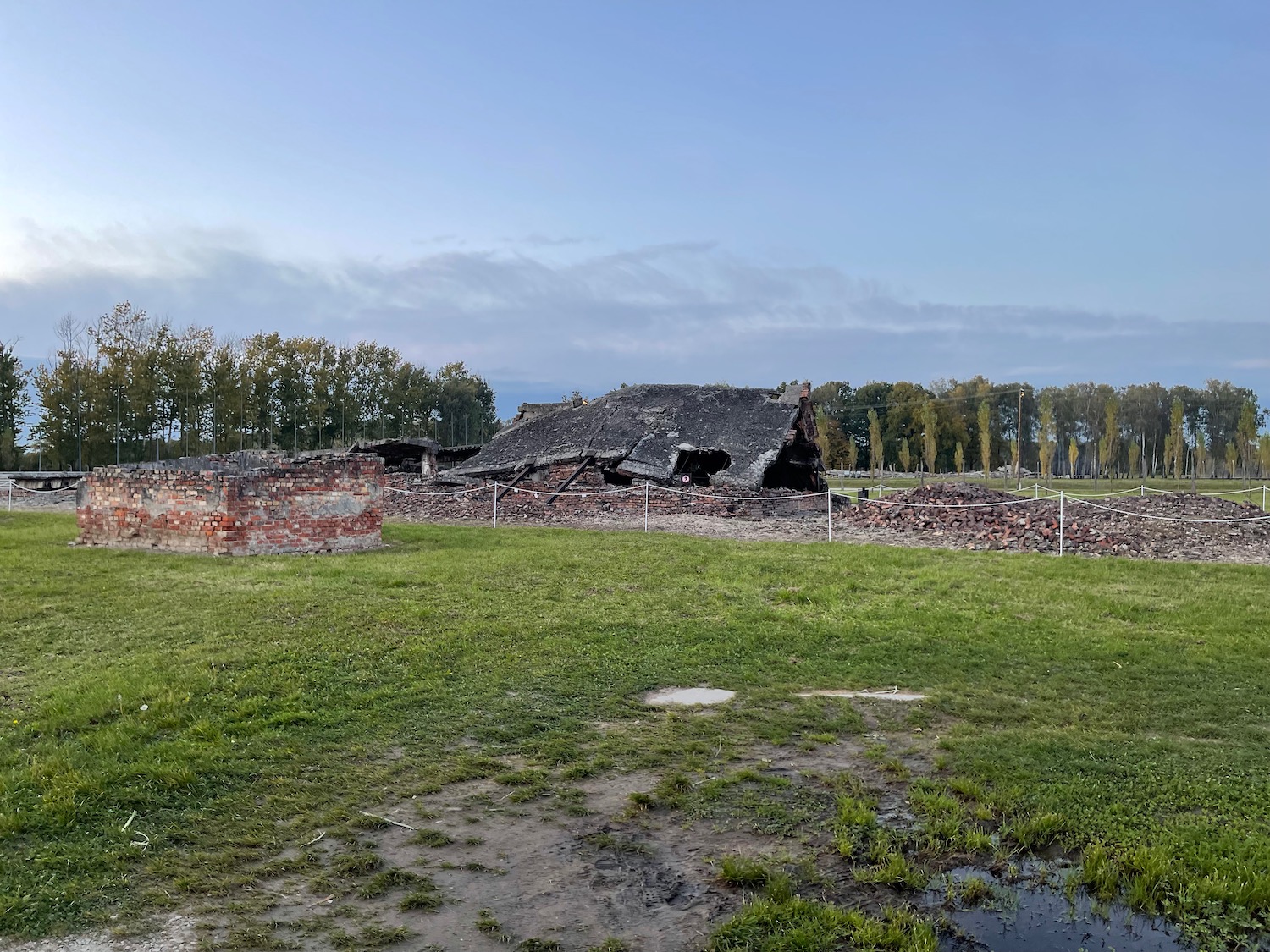 a destroyed building with a brick wall and a brick building in the background