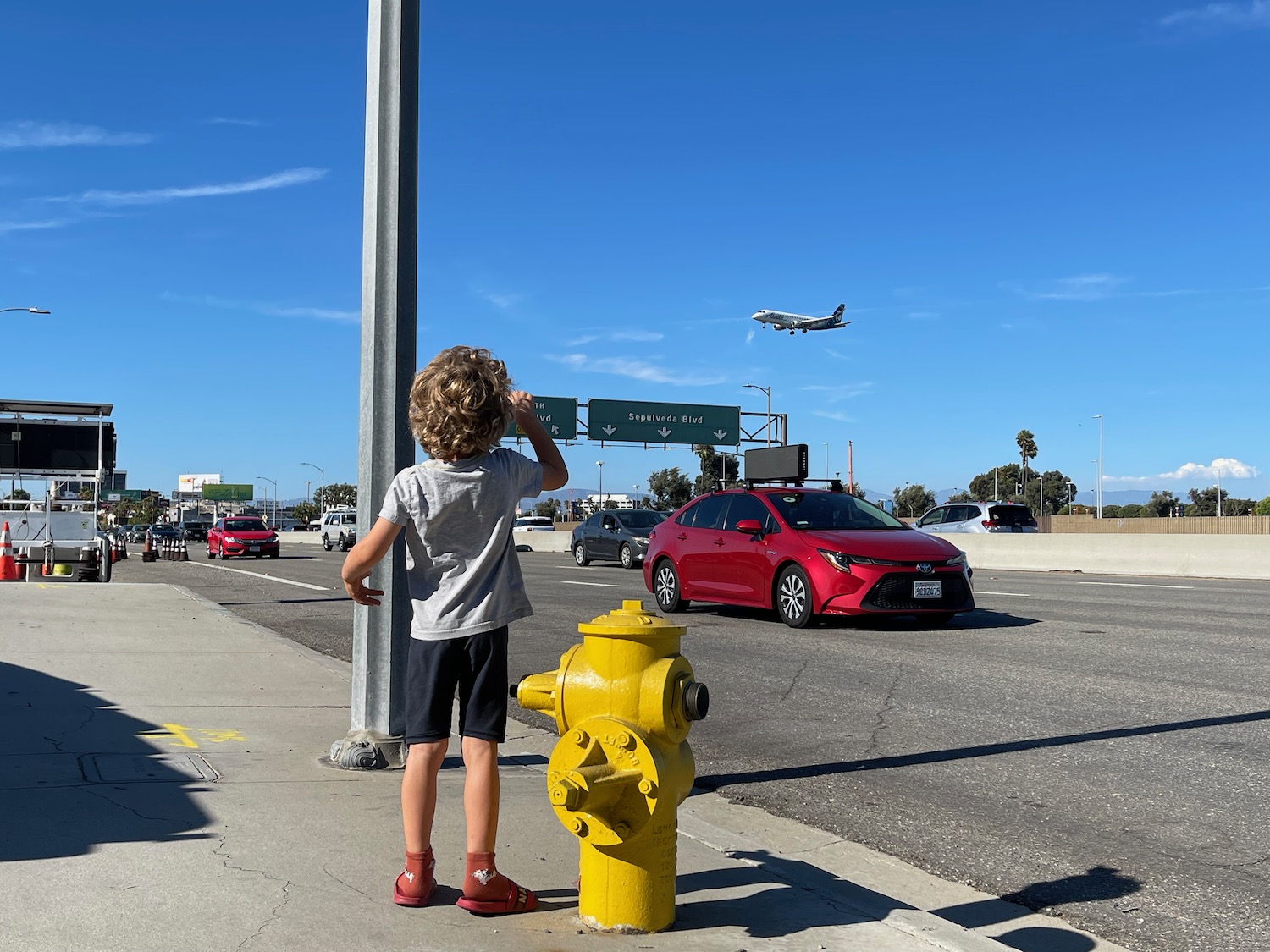 a child standing on a sidewalk next to a fire hydrant