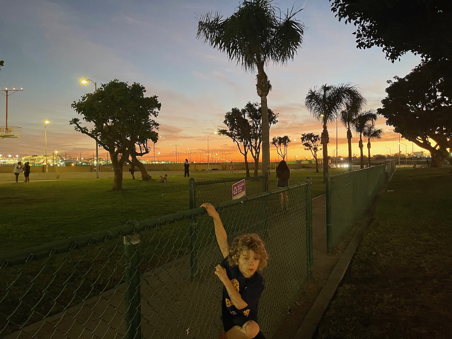 a boy leaning on a fence