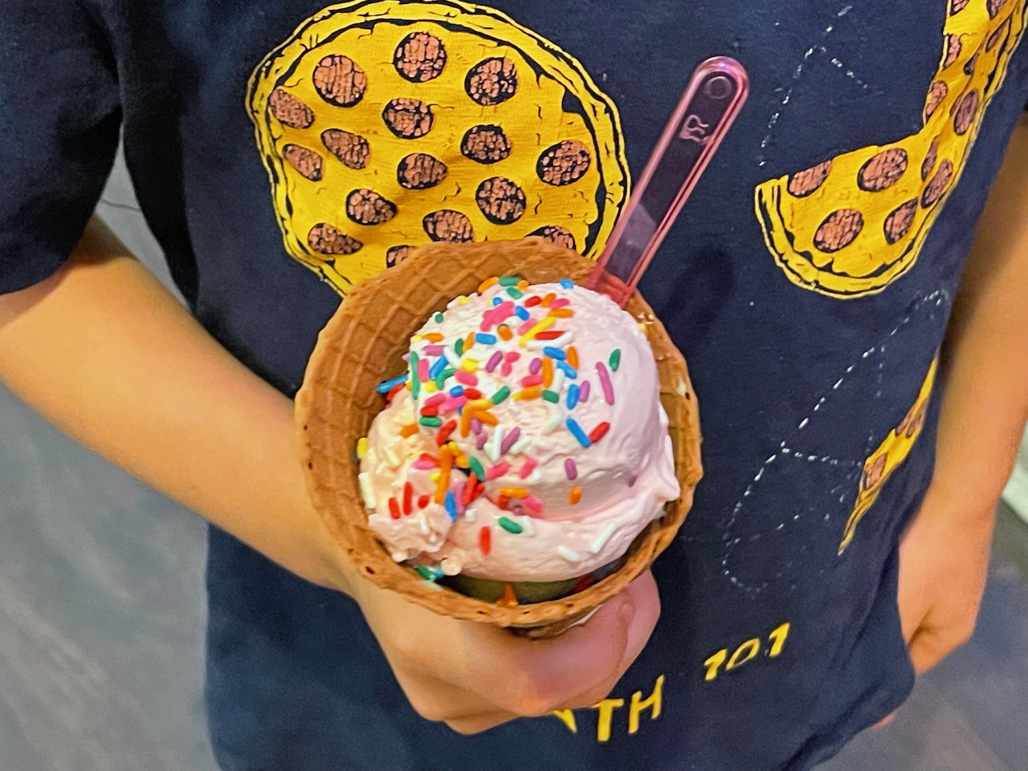 a person holding a ice cream cone with sprinkles