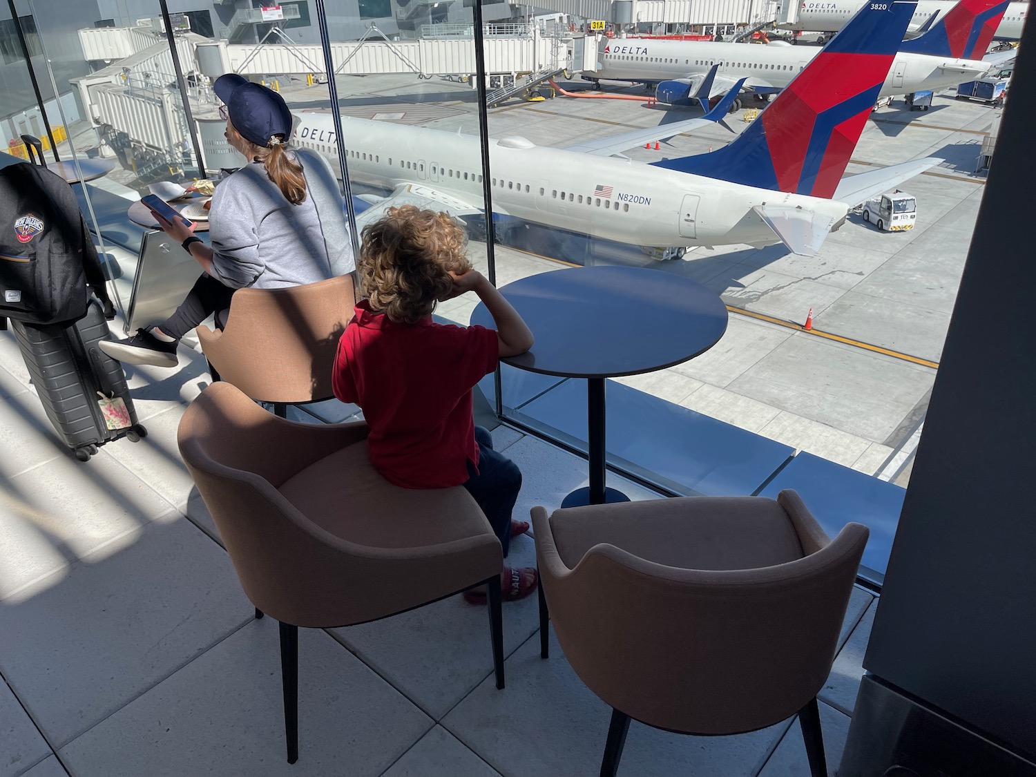 a woman and child sitting at tables and chairs in an airport