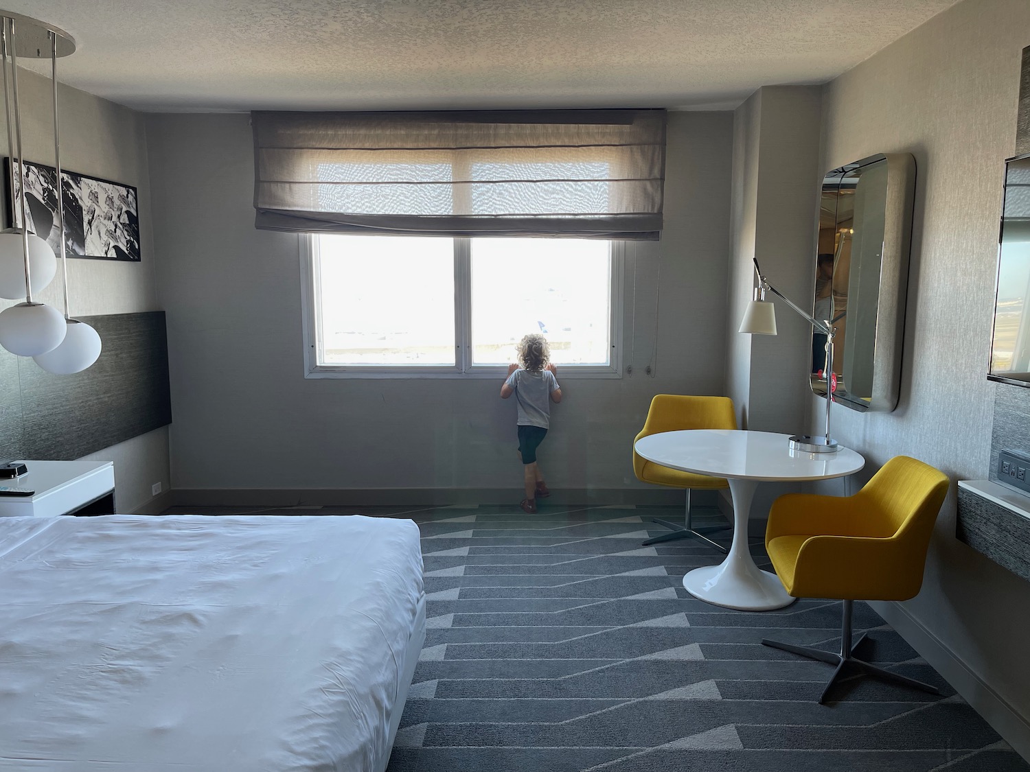 a child standing in a room with a window and yellow chairs