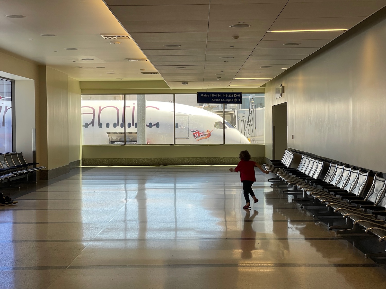 a child walking in a hallway with chairs
