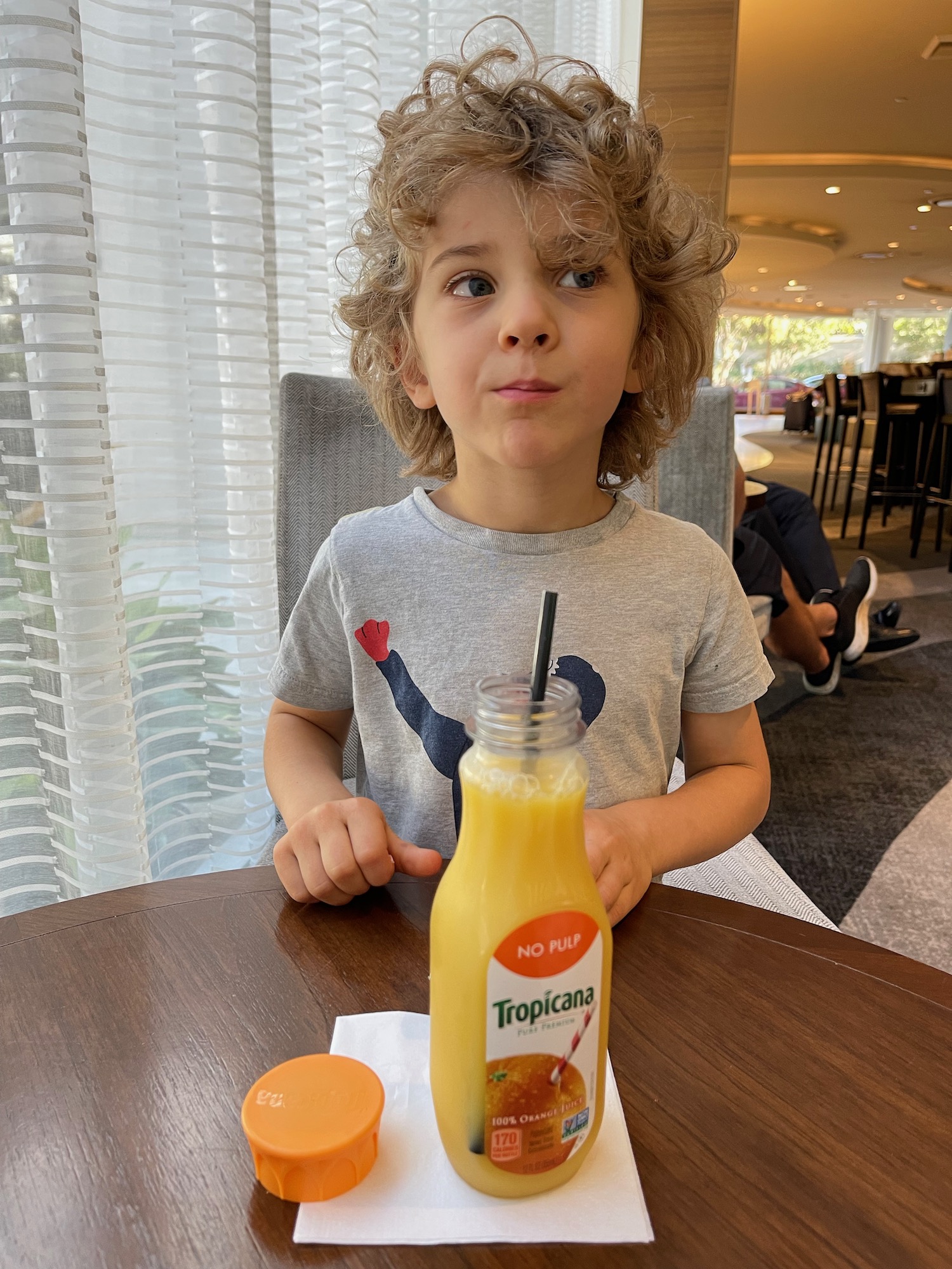 a child sitting at a table with a drink