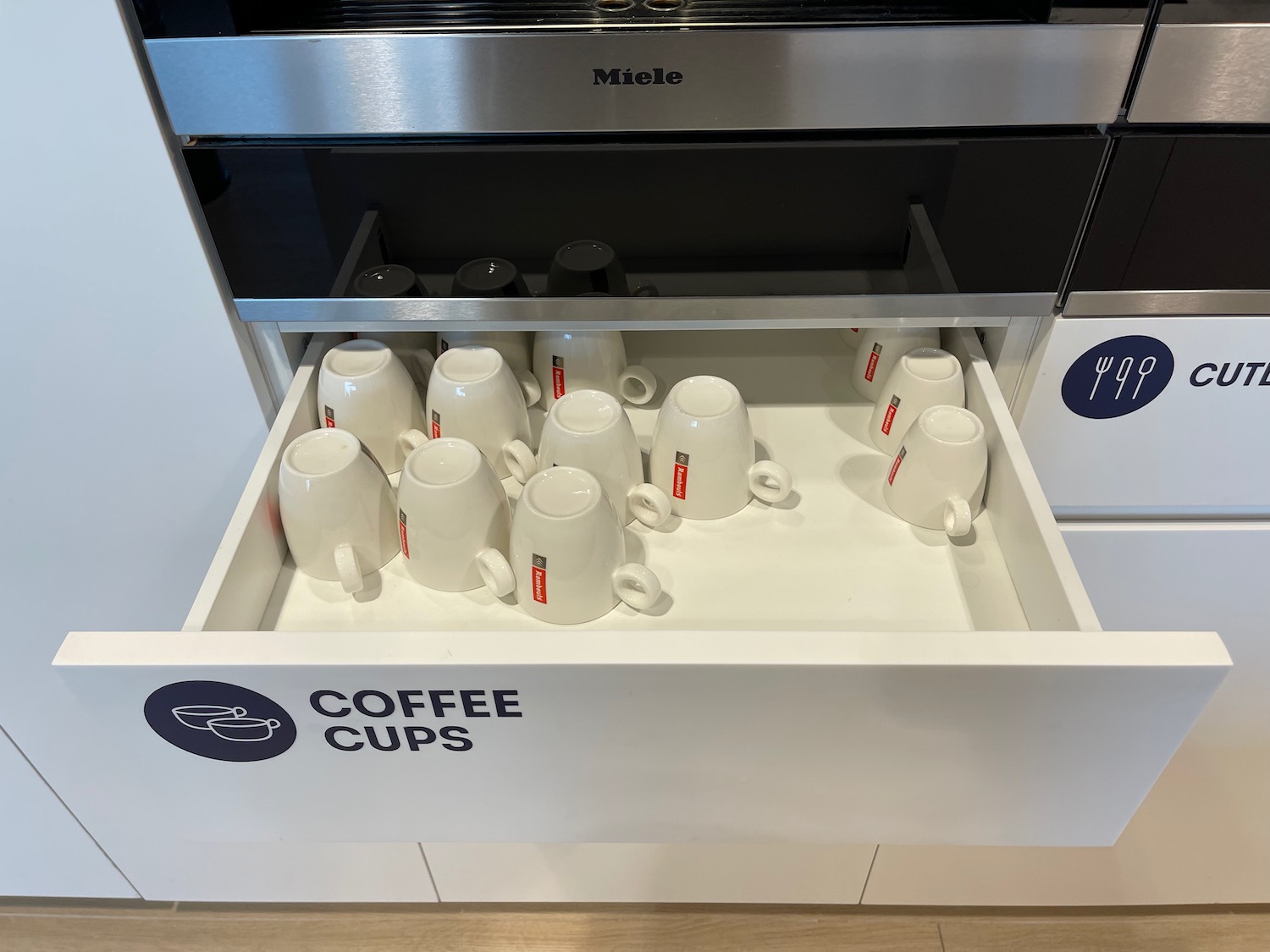 a drawer with white mugs in it