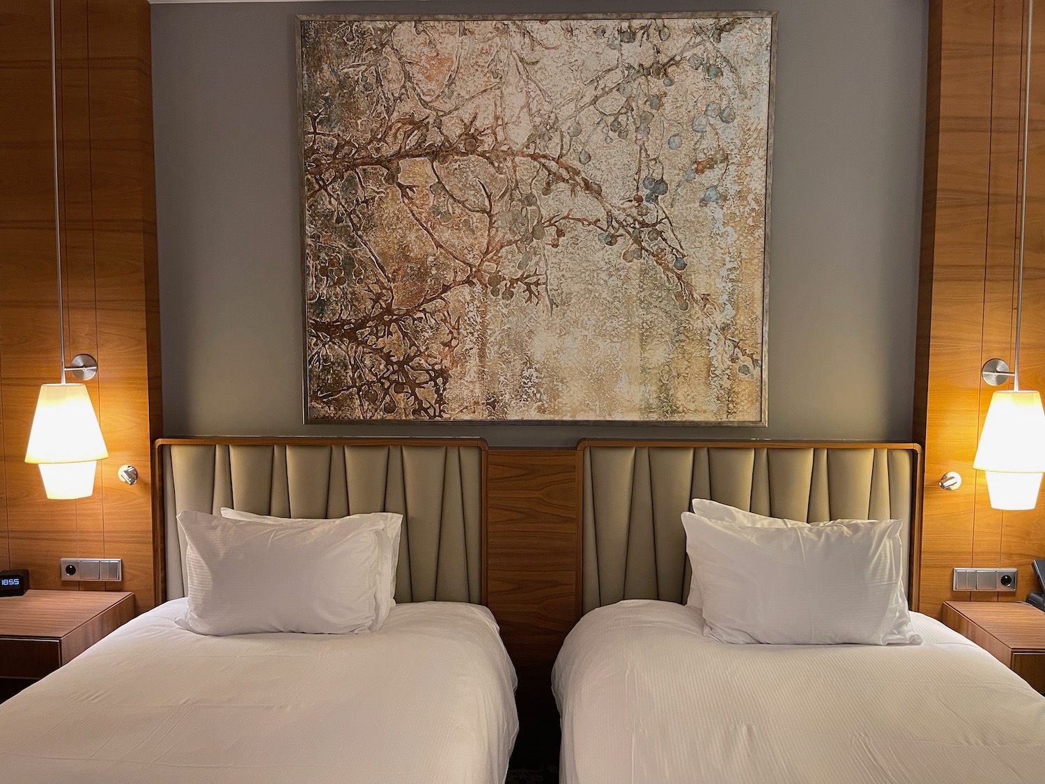 two beds with pillows and a painting on the wall