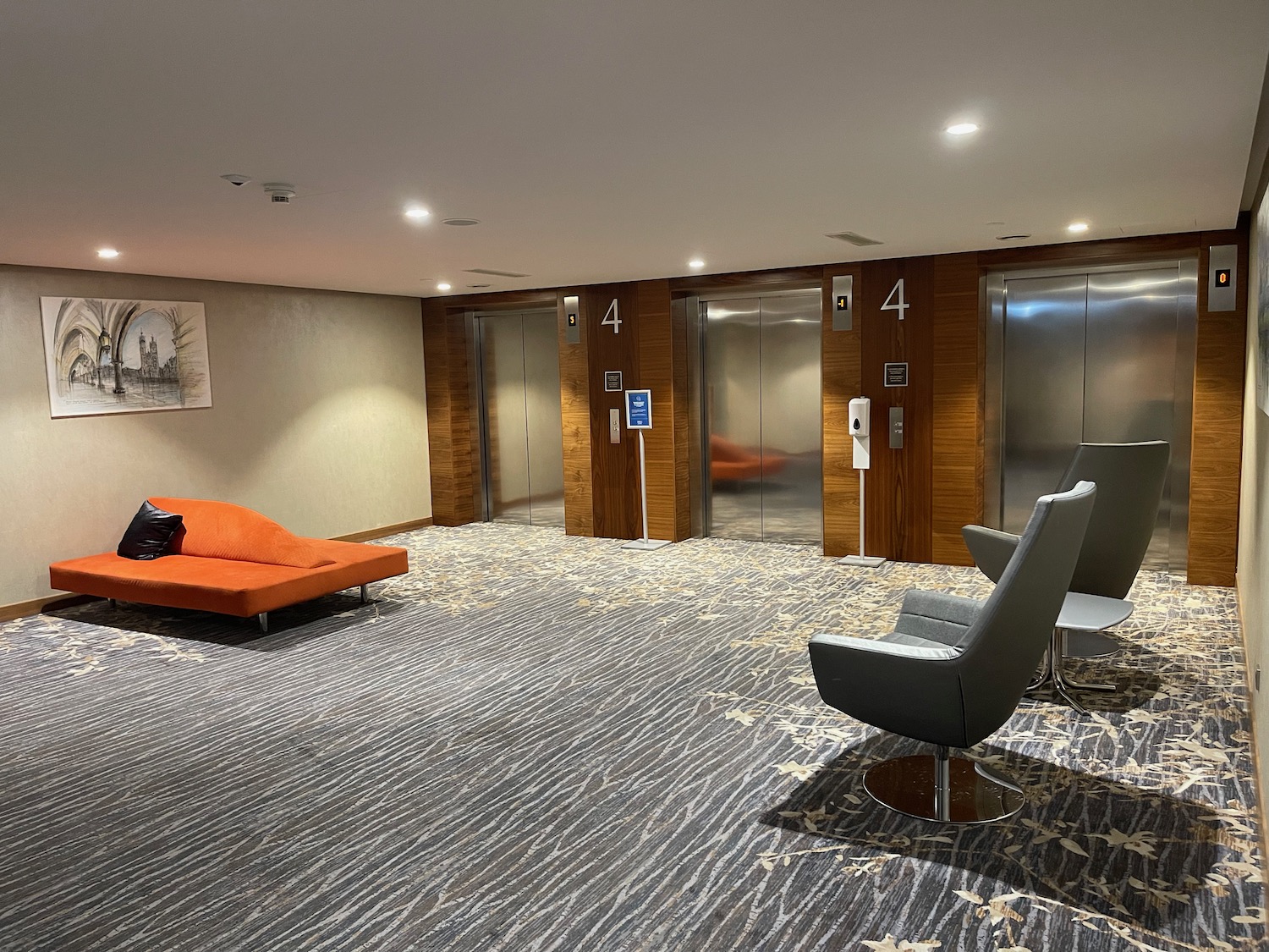 an empty lobby with an orange couch and chairs