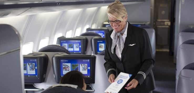 a woman in flight attendant giving a piece of paper to a woman in an airplane