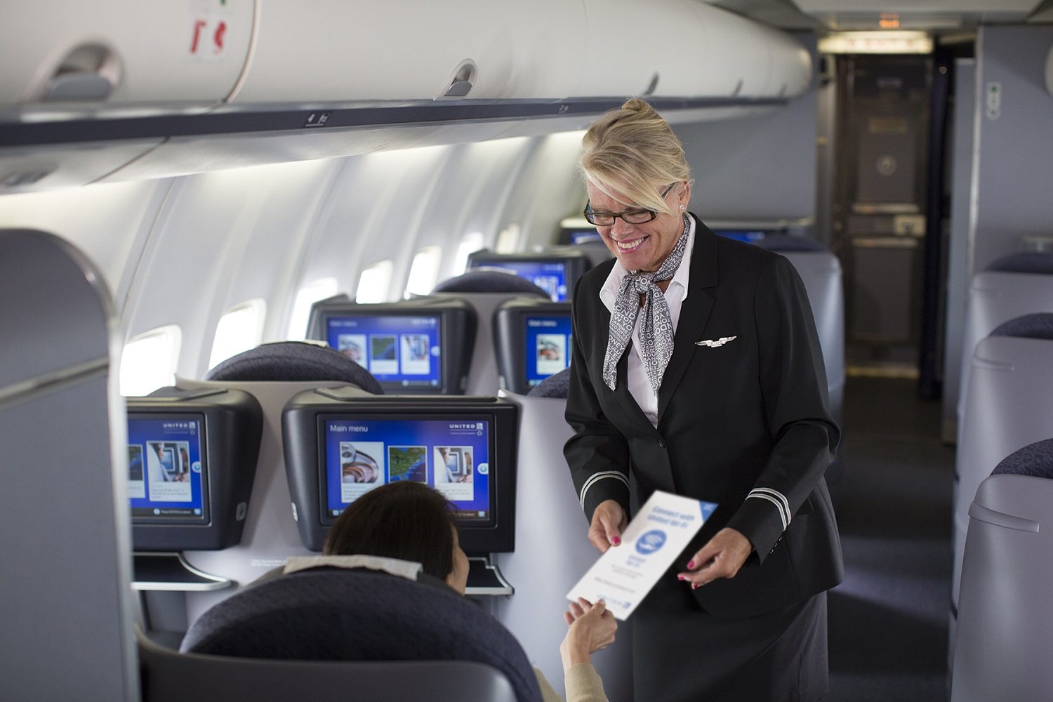 a woman in flight attendant giving a piece of paper to a woman in an airplane
