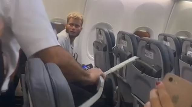 a man in a white shirt and glasses on a plane