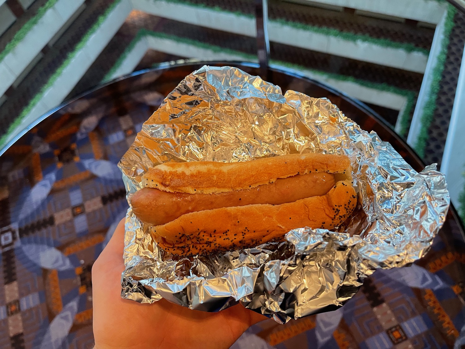 a hand holding a hot dog in foil