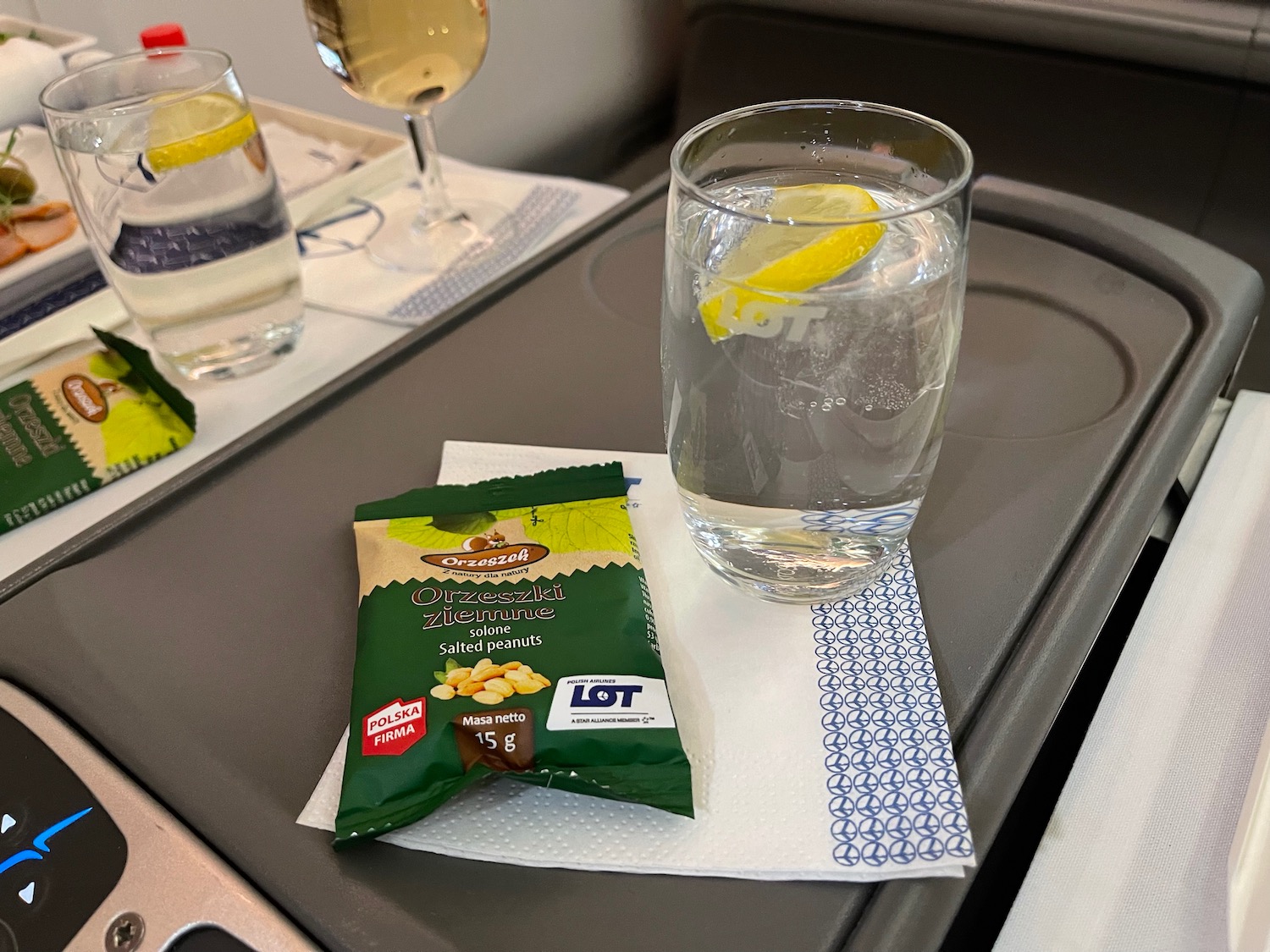 a glass of water and a bag of peanuts on a tray