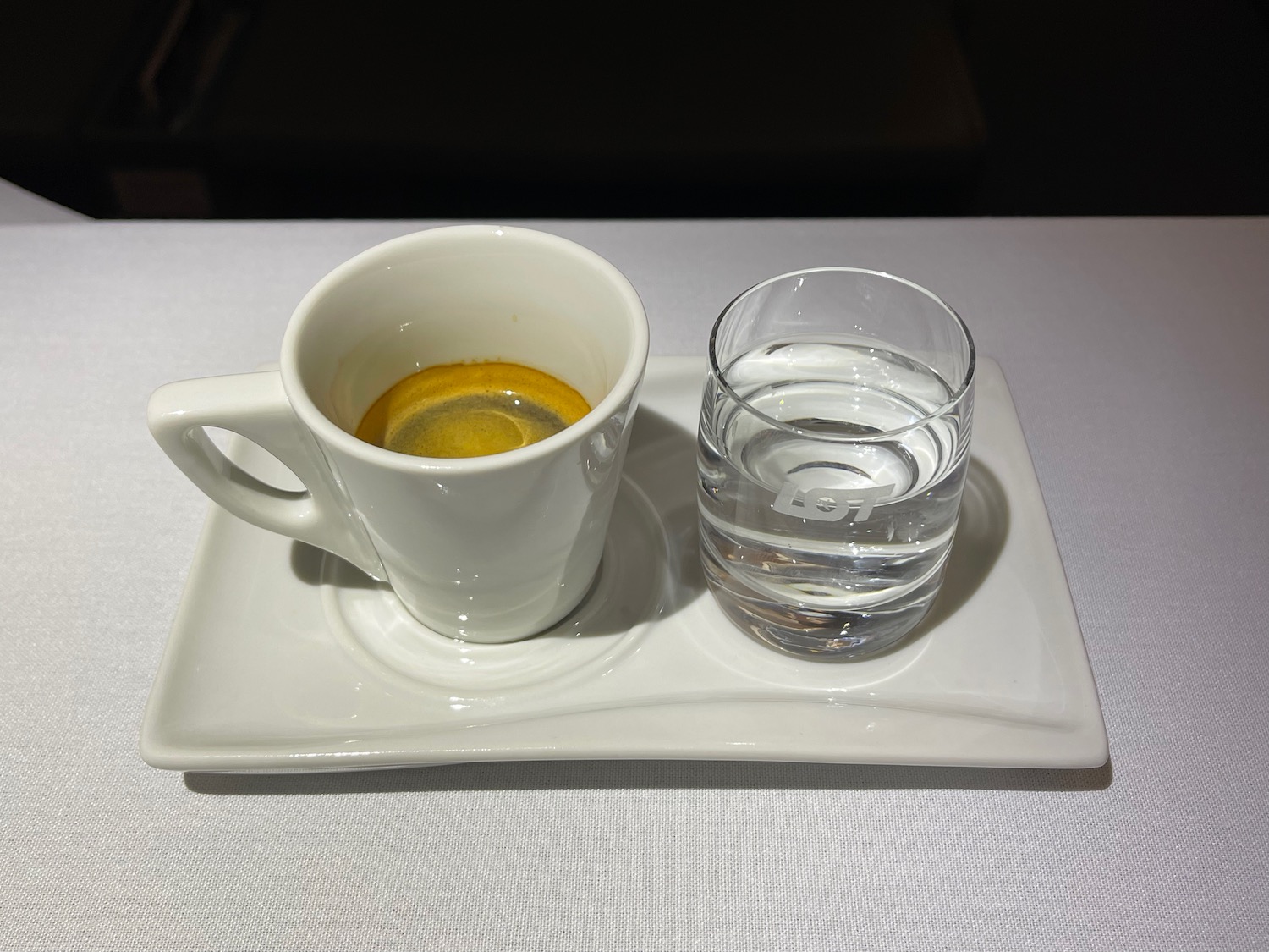 a white cup and glass of water on a white plate