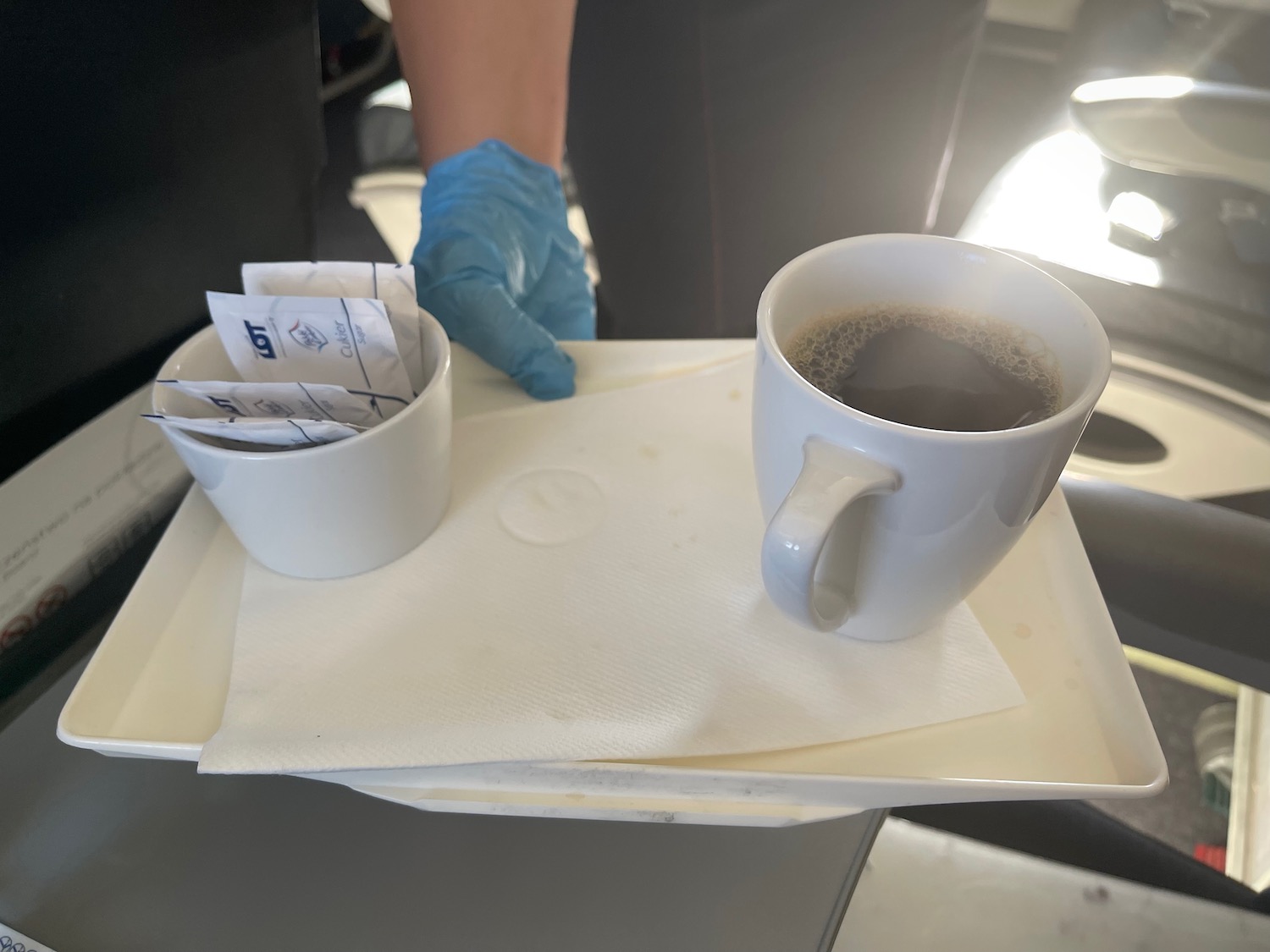 a tray with a cup of coffee and a gloved hand