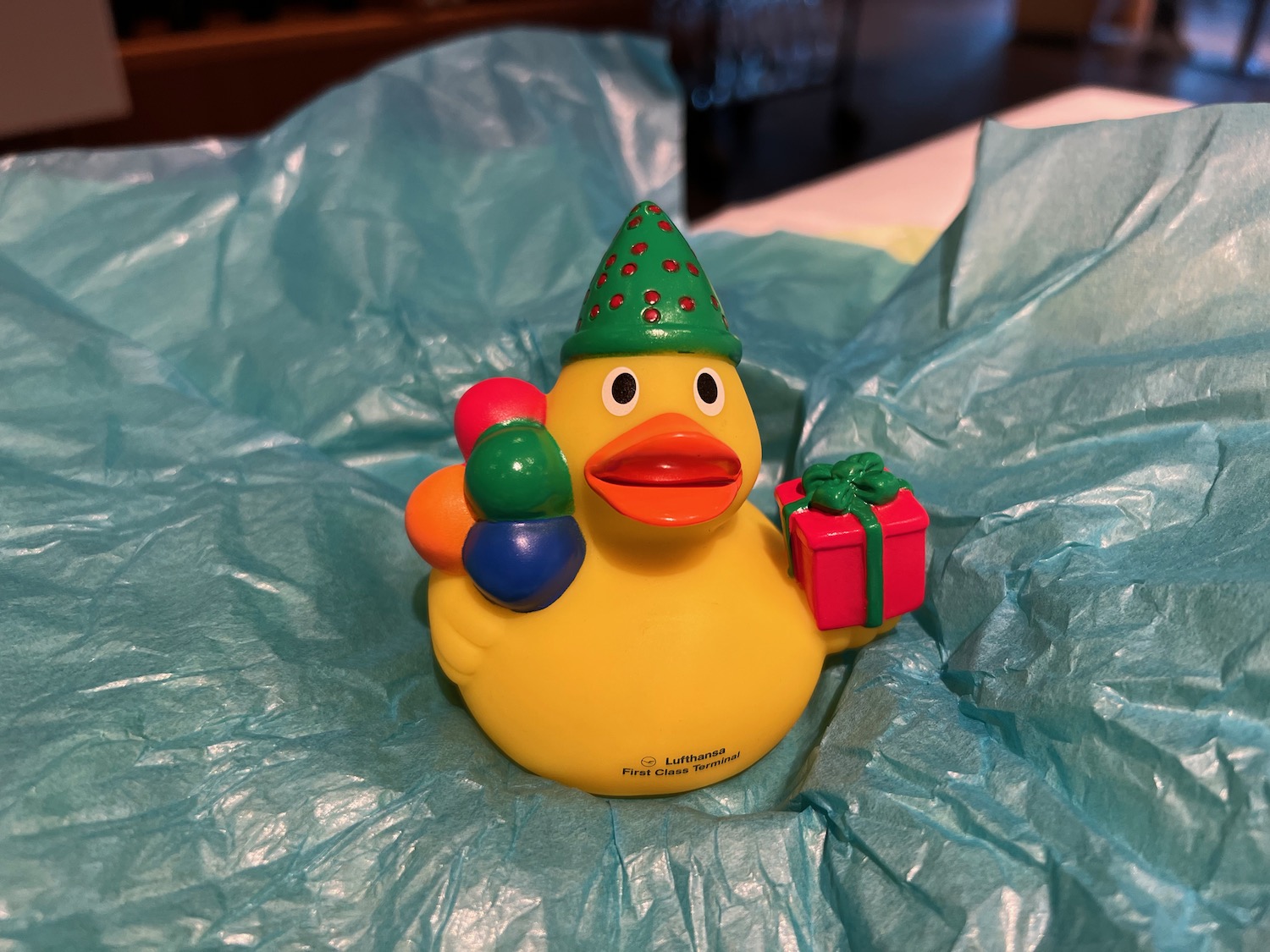a yellow rubber duck with a hat and a present on a blue paper