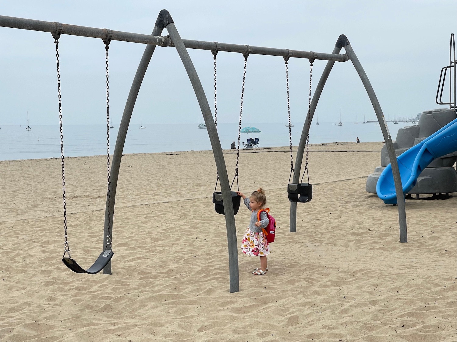 a girl playing on a swing set at a beach