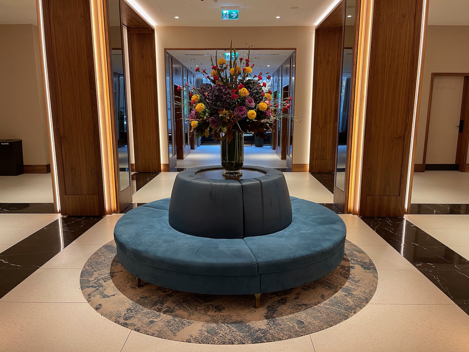a vase of flowers on a round blue couch in a hallway
