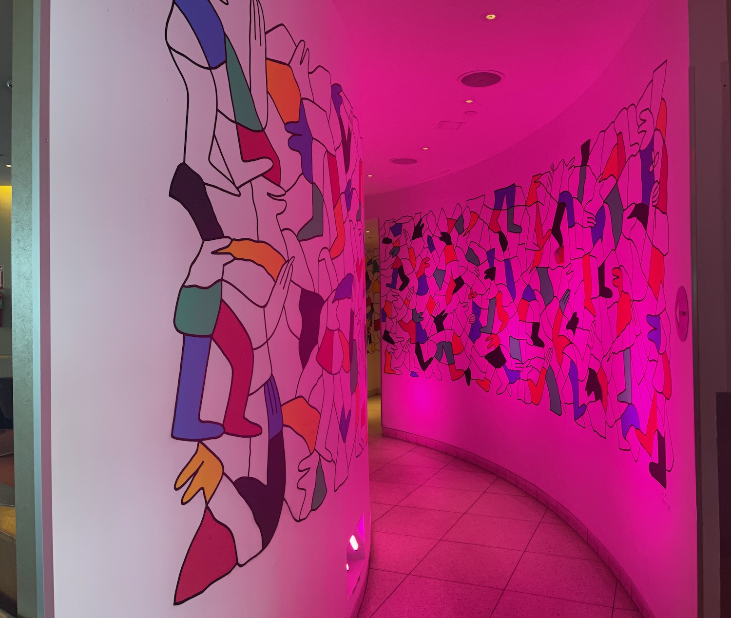 a hallway with a wall with colorful artwork on it