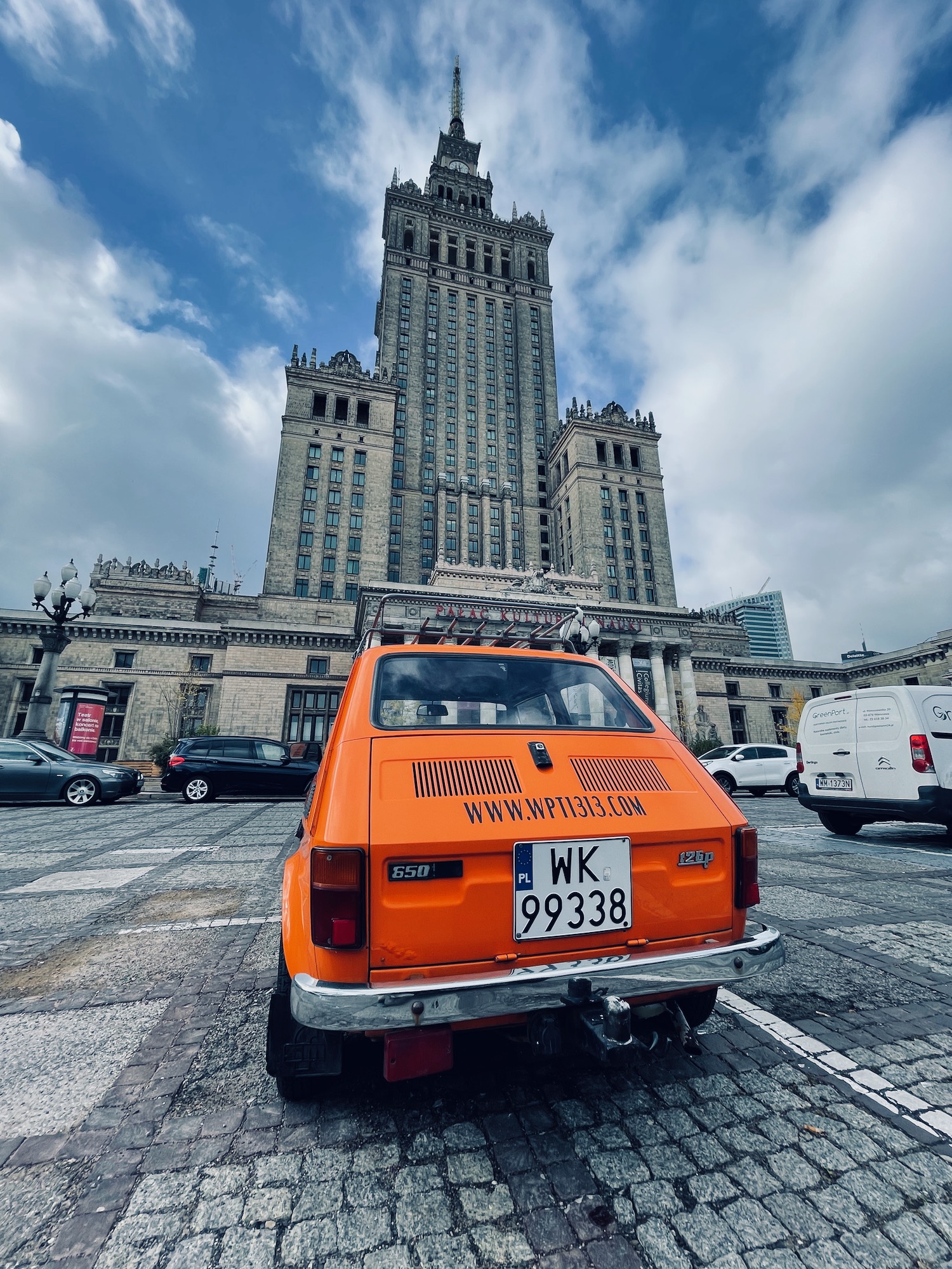 an orange car parked in front of a large building