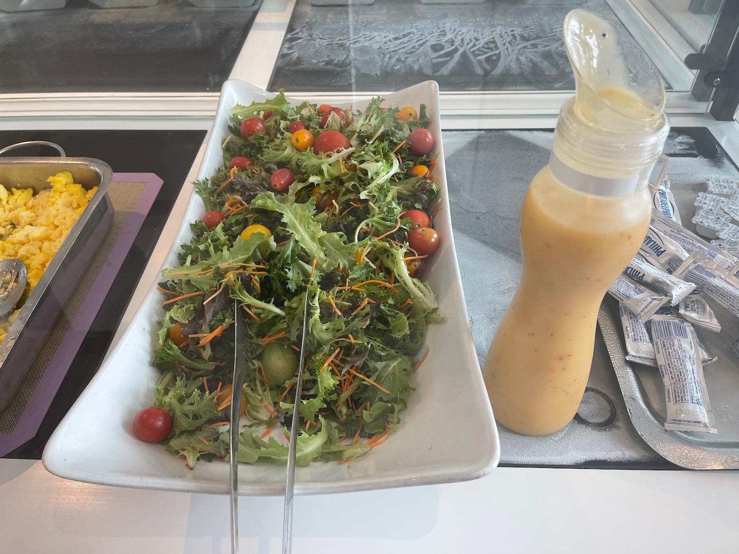 a salad in a bowl next to a bottle of liquid