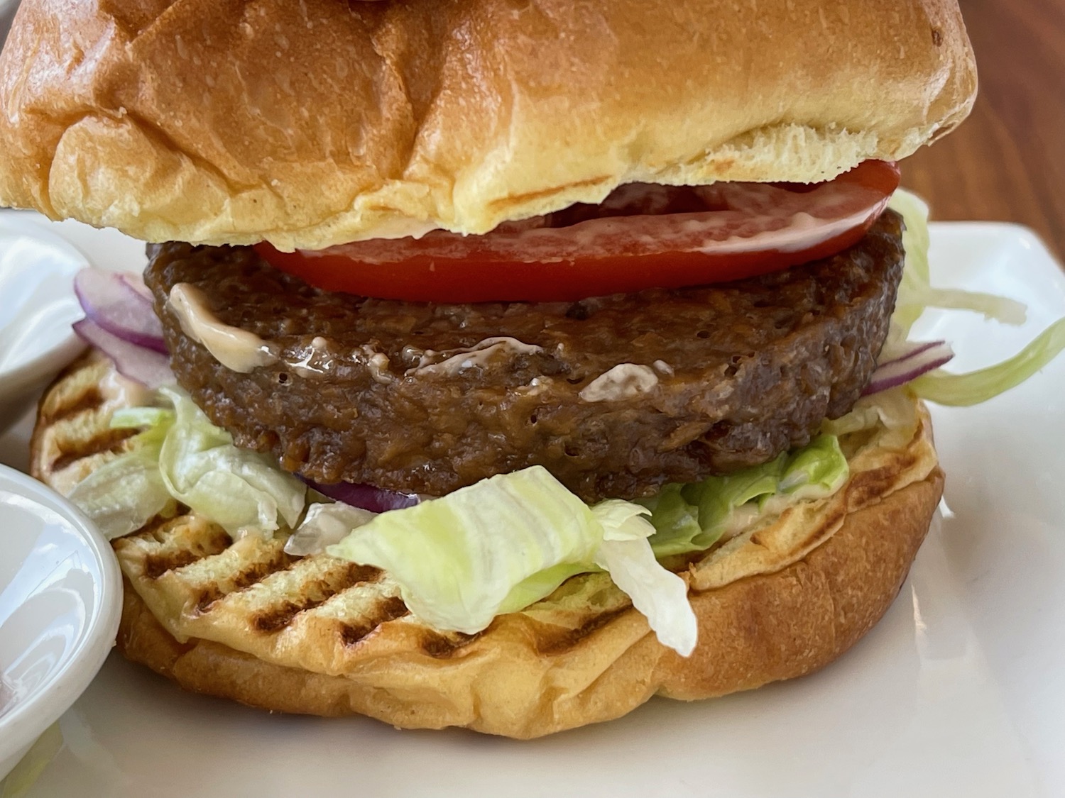 a burger with lettuce and tomato on a white plate