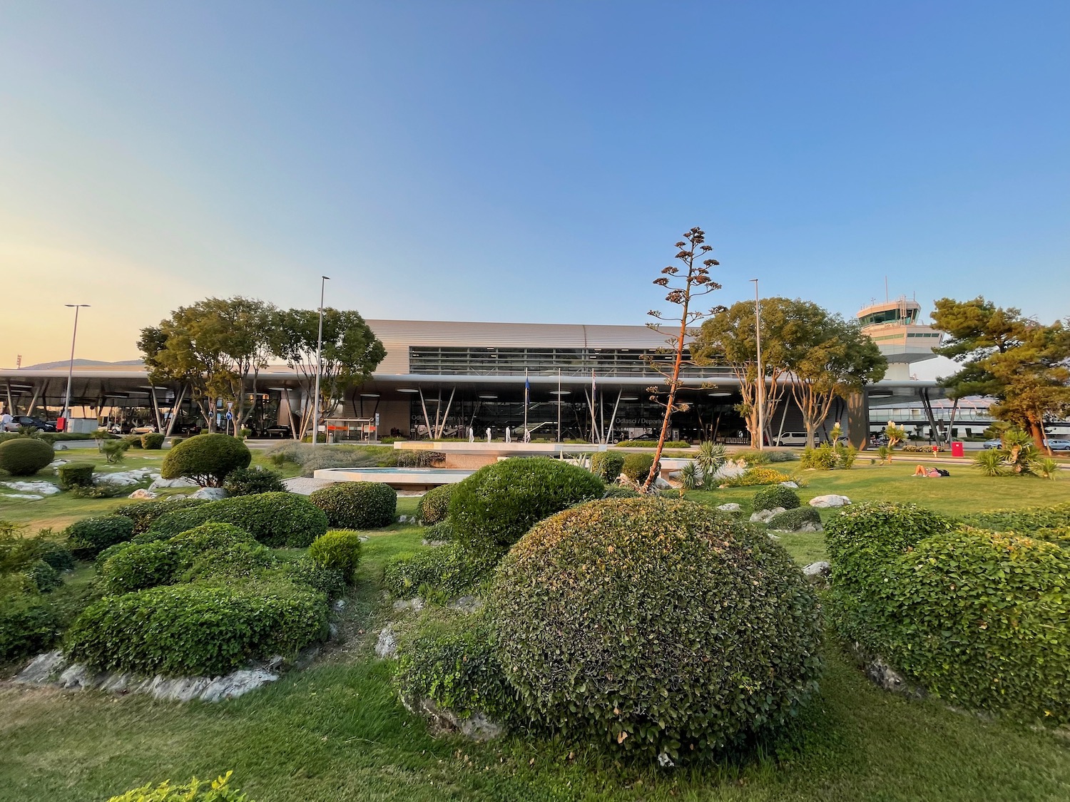 a landscape with bushes and a building