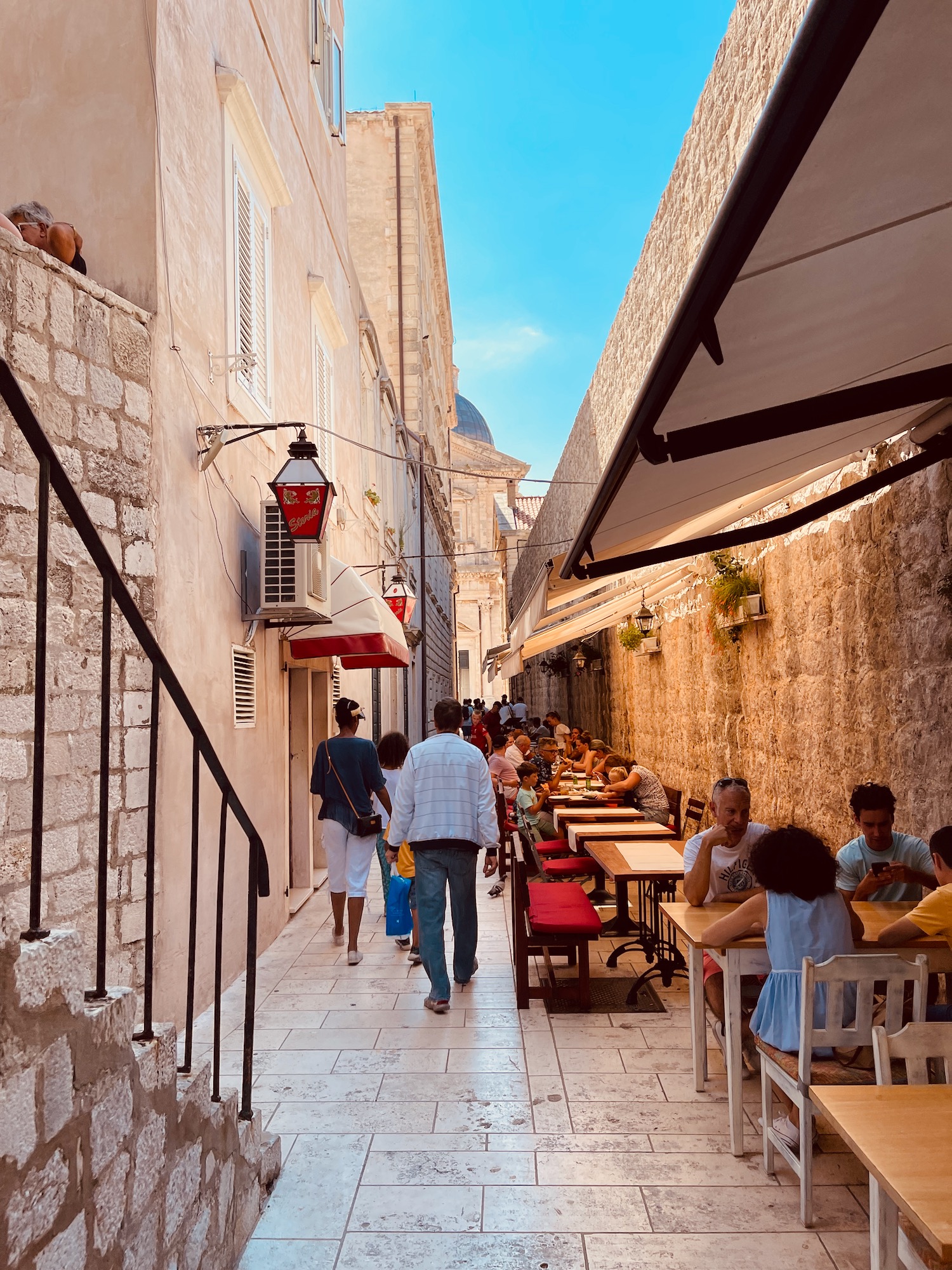 a group of people sitting at tables in a narrow alley