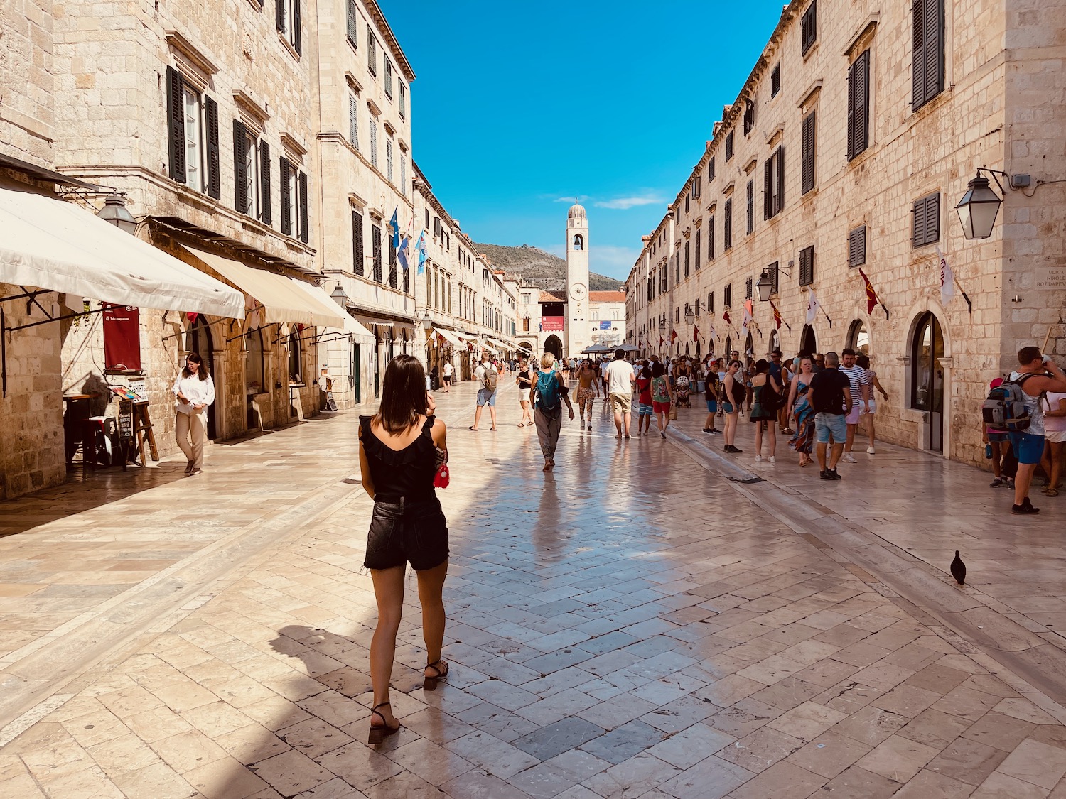 a group of people walking down a street with Stradun in the background