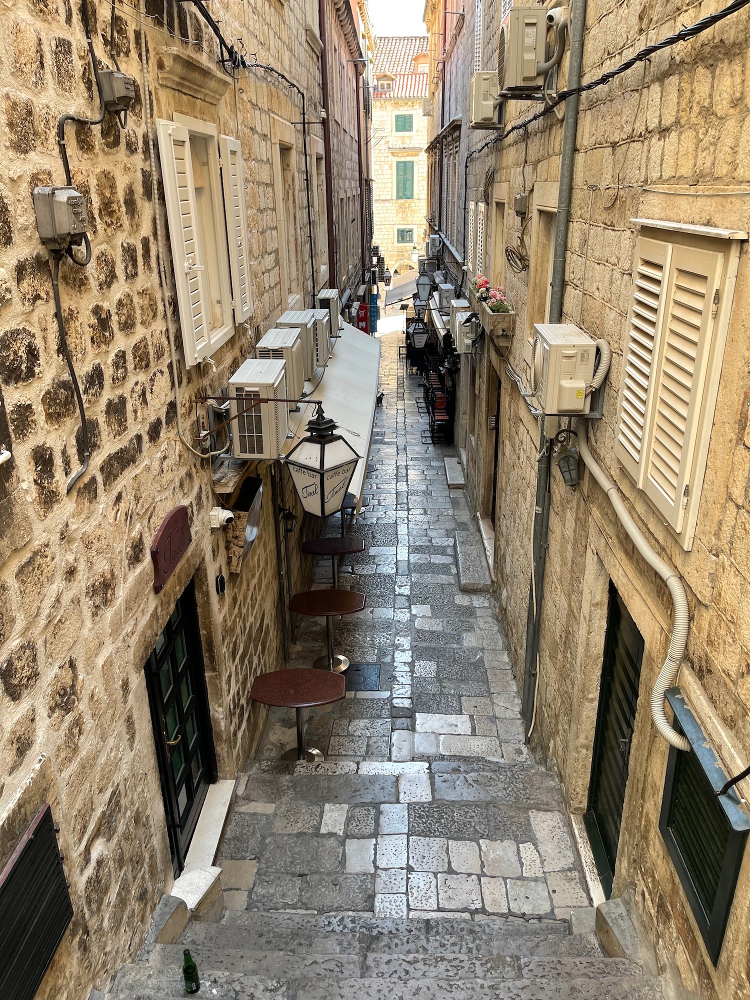 a stone alleyway with tables and chairs