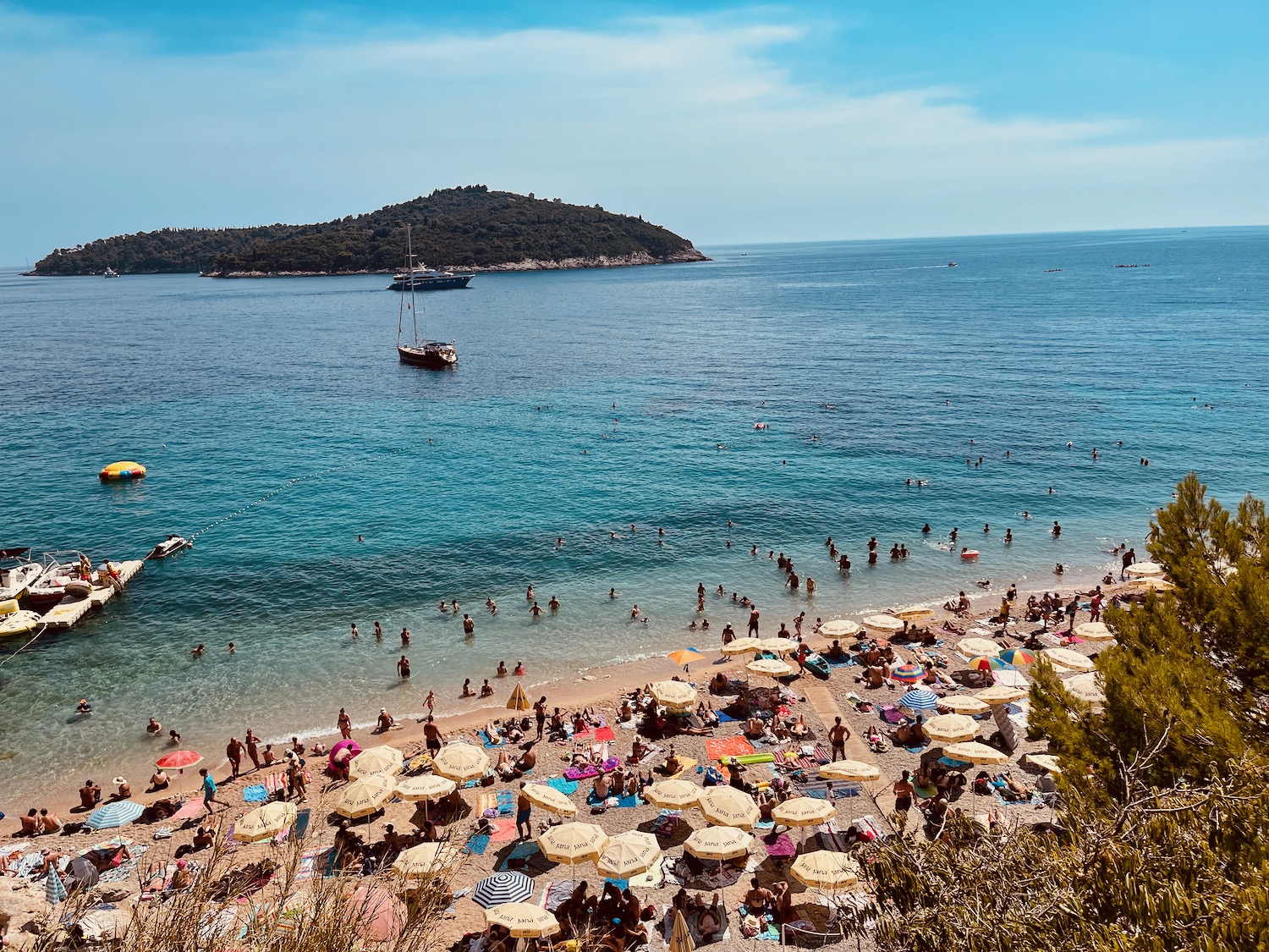 a beach with many people and umbrellas