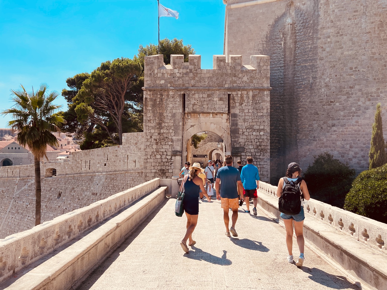 a group of people walking on a bridge over a stone wall