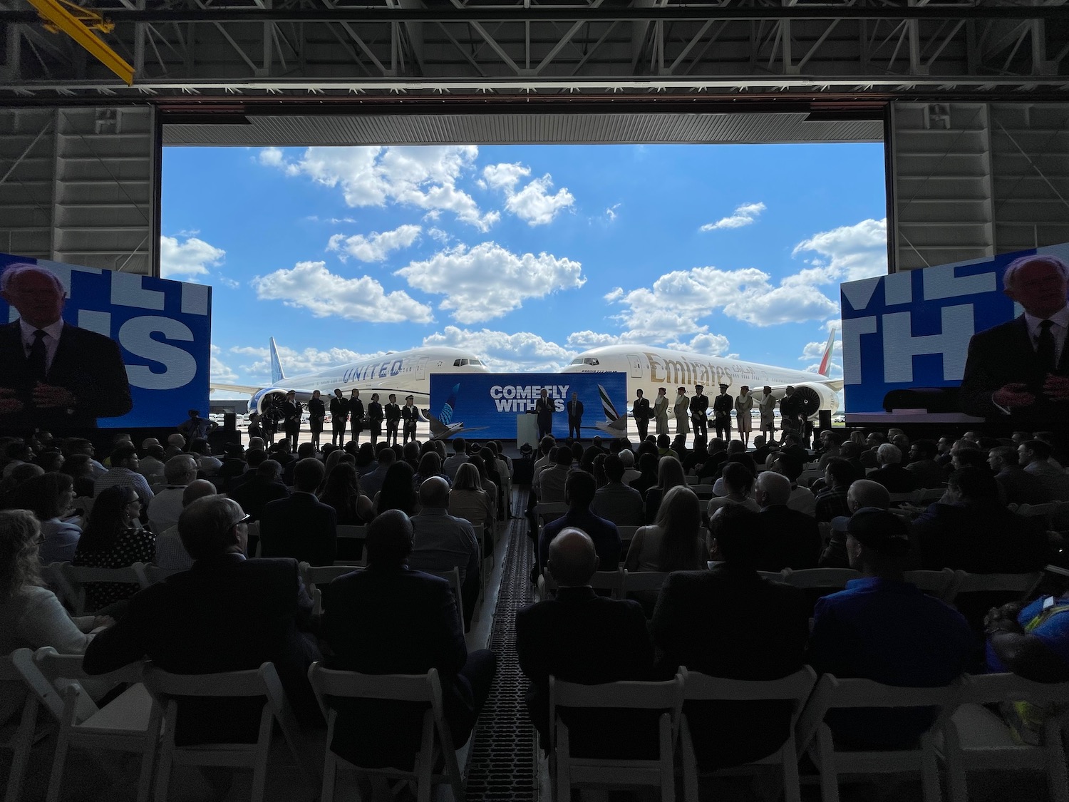 a group of people in a hangar with an airplane in the background