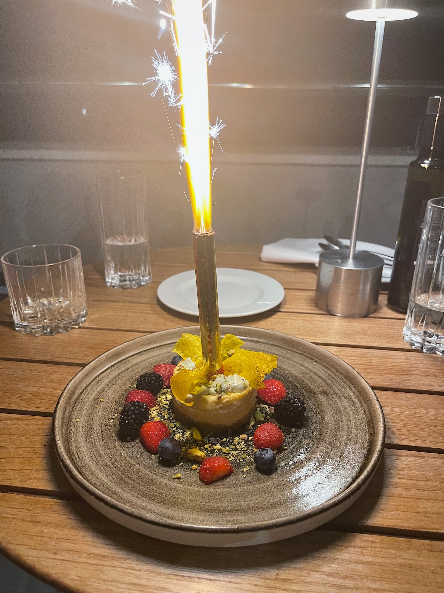 a lit candle on a plate with fruit and berries