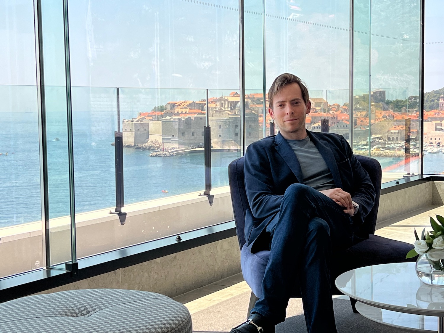 a man sitting in a chair by a window with a view of the ocean