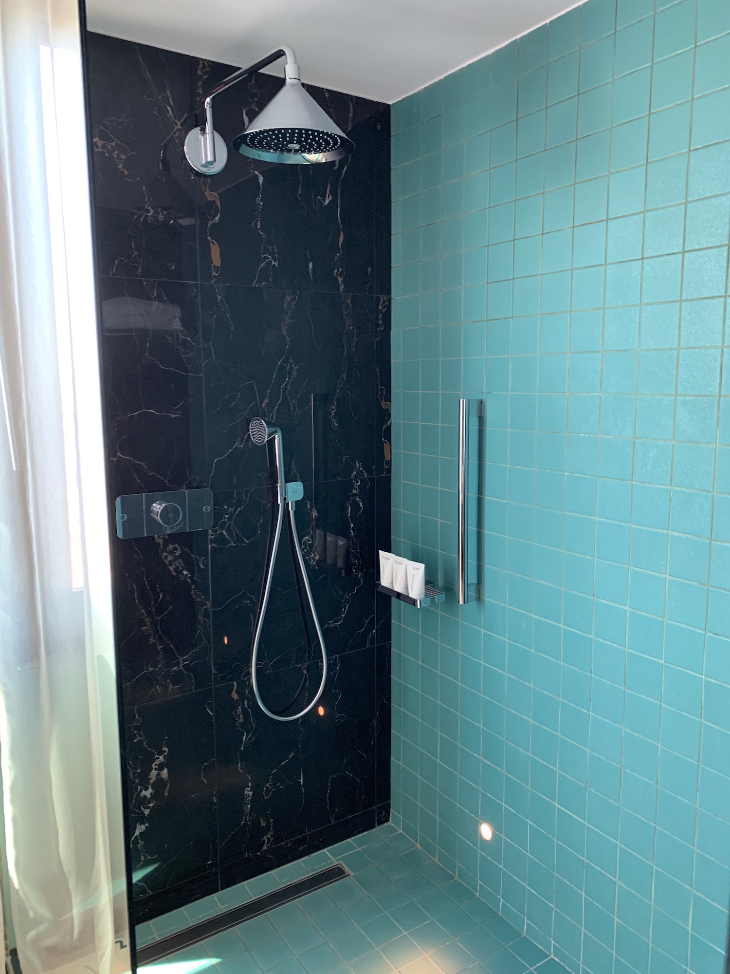 a shower with a shower head and a blue tile wall