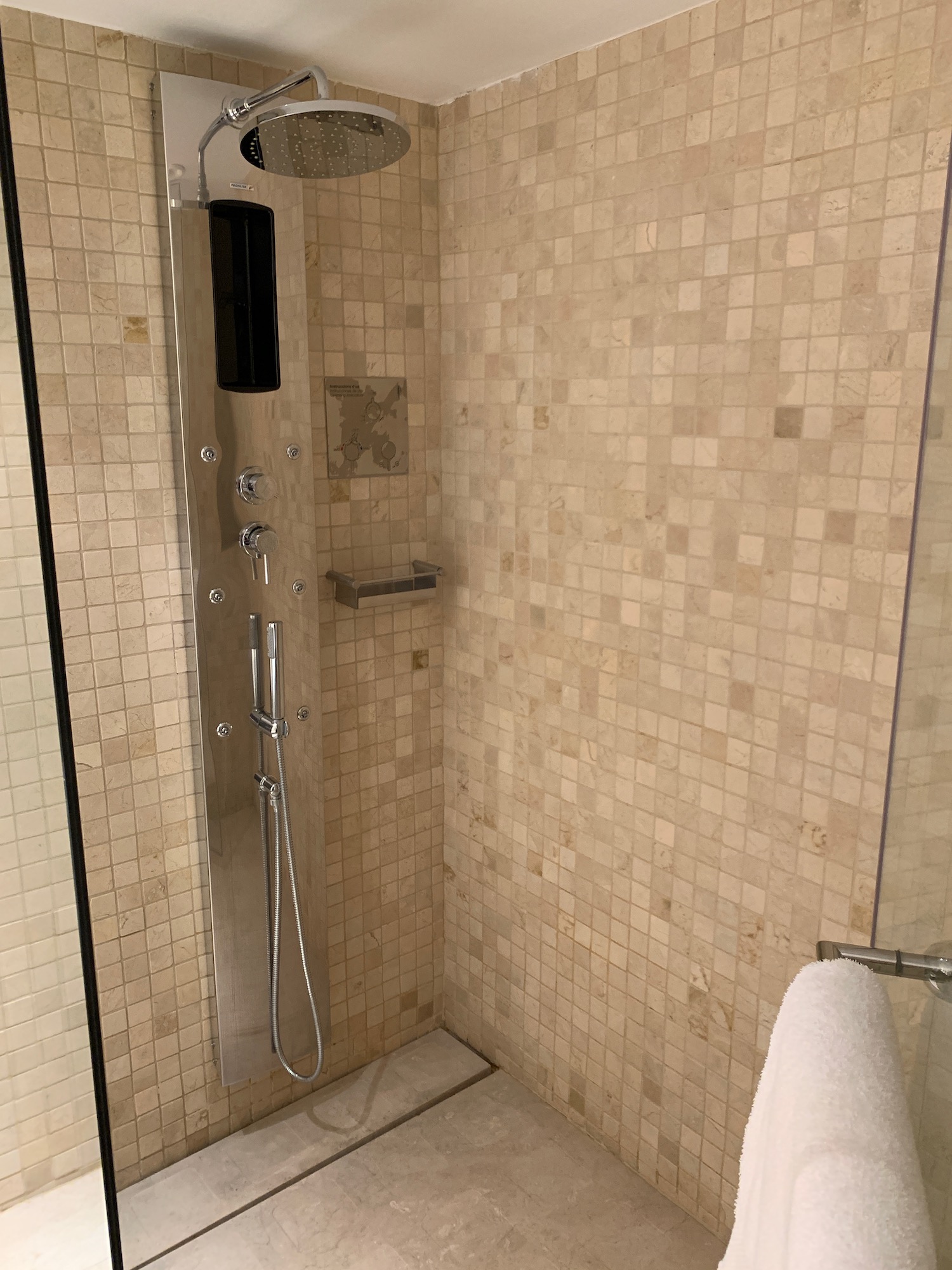 a shower with a shower head and a white towel