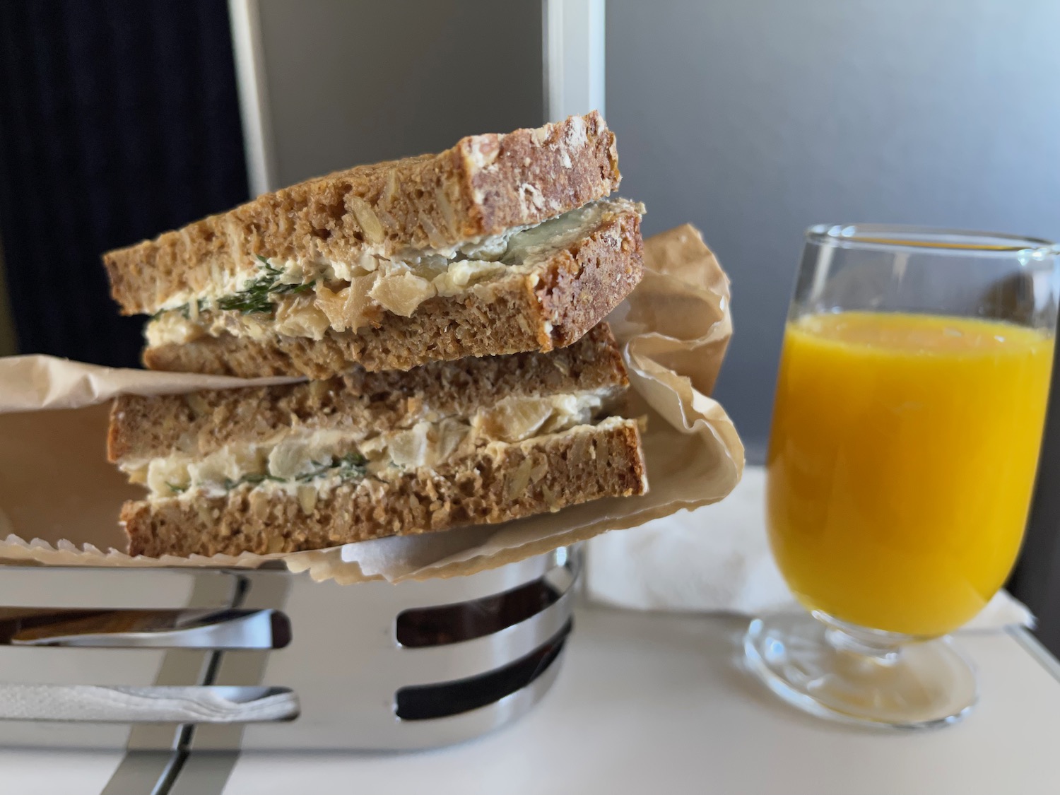 a sandwich on a napkin next to a glass of orange juice