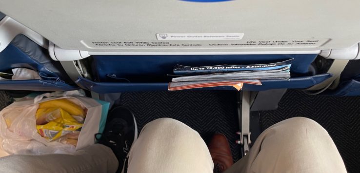 a person's legs and a bag of food on the side of a plane