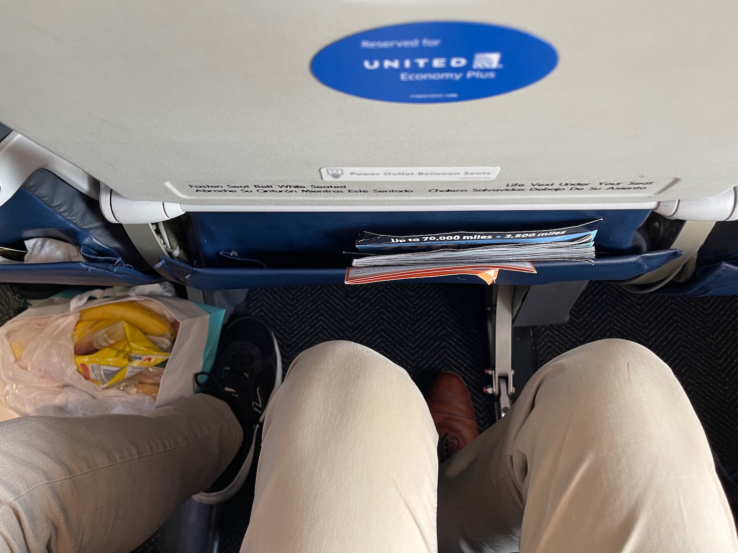 a person's legs and a bag of food on the side of a plane