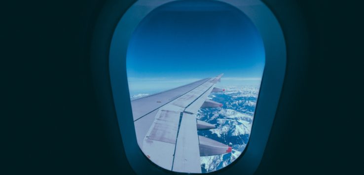 a plane wing with snow covered mountains in the background