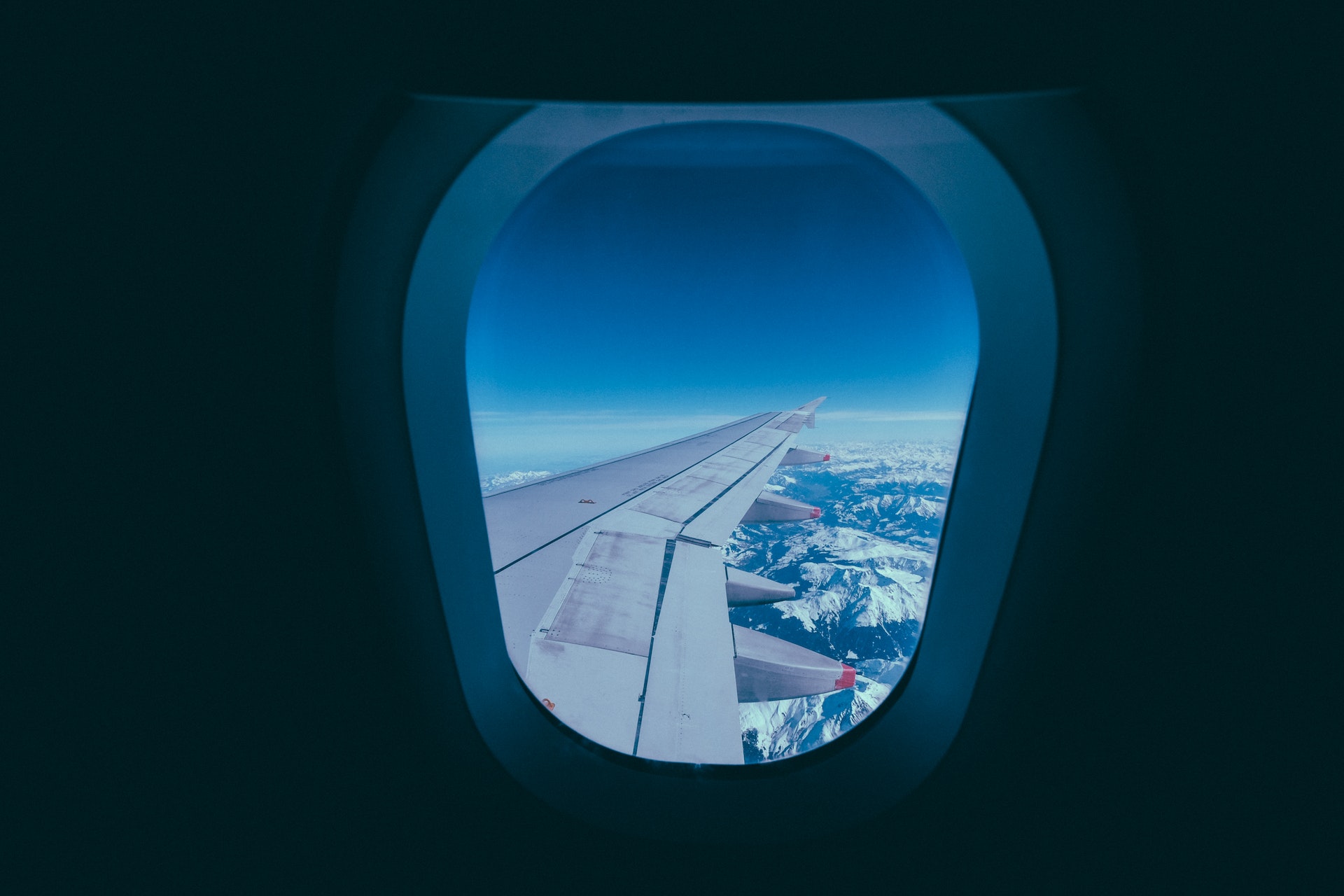 a plane wing with snow covered mountains in the background