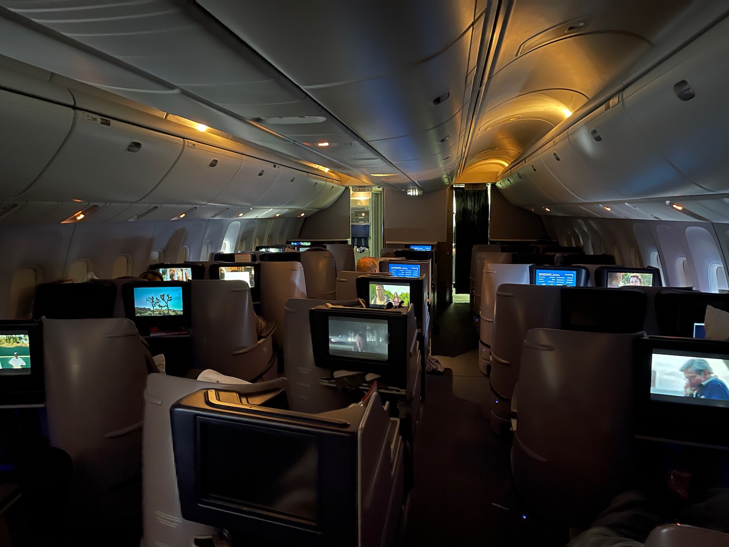 a row of seats with monitors on the side of the plane