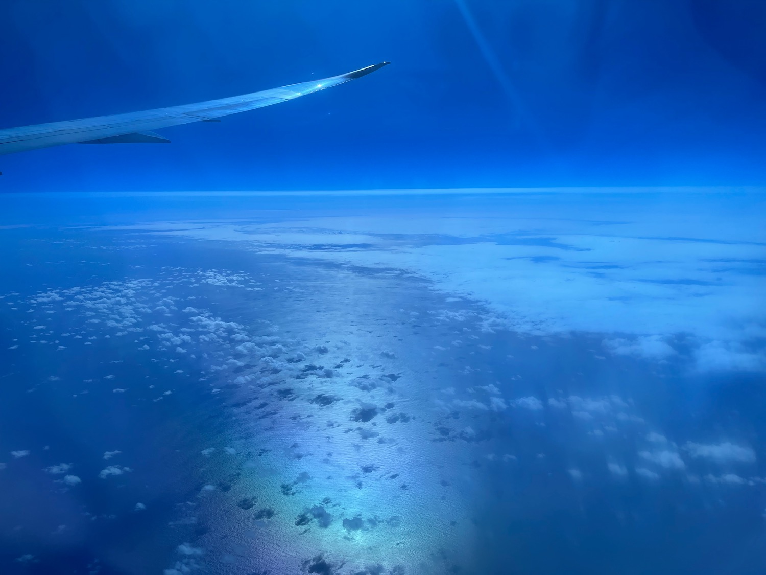 an airplane wing above the ocean