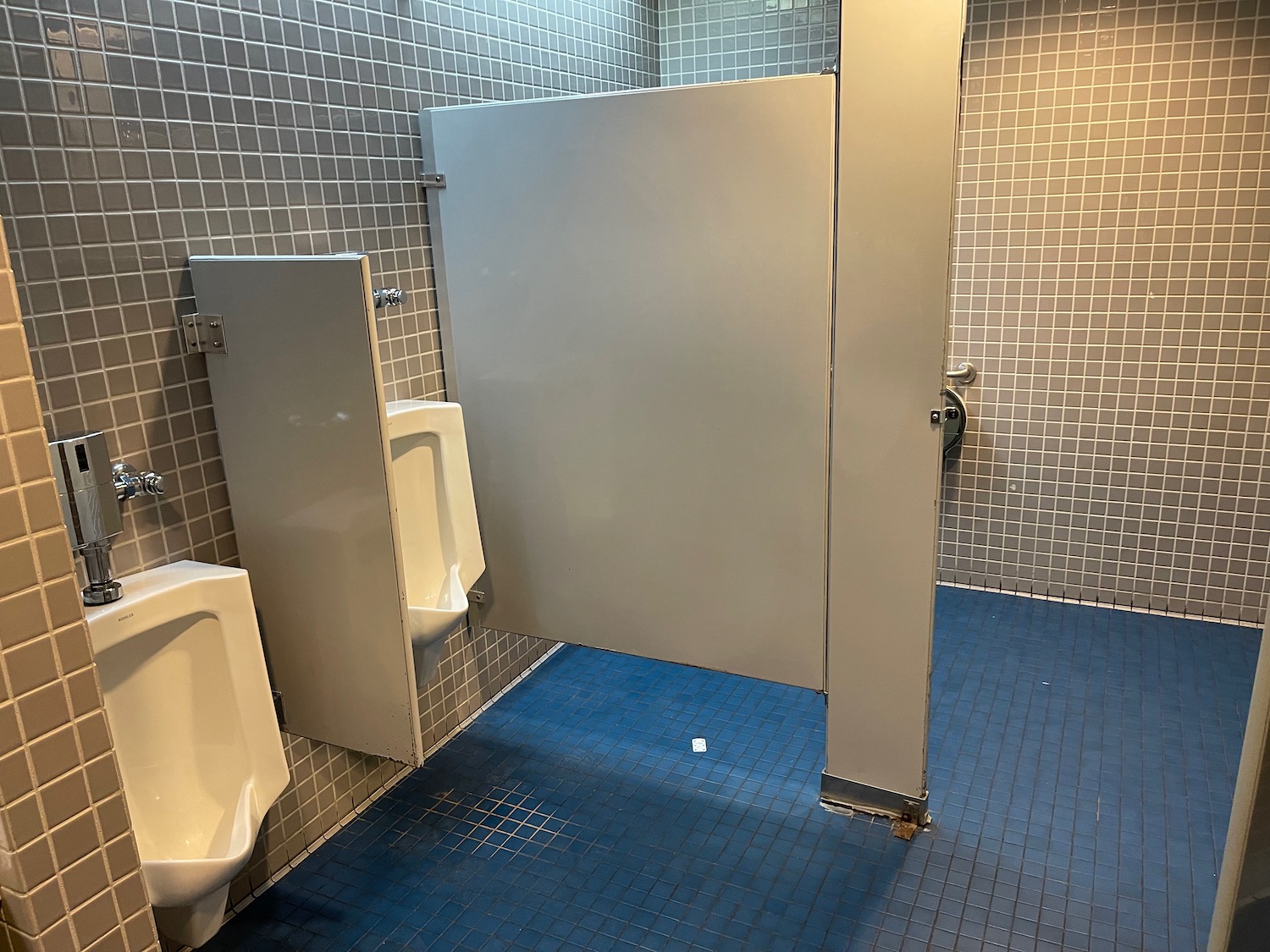 a bathroom with a urinal and a white door