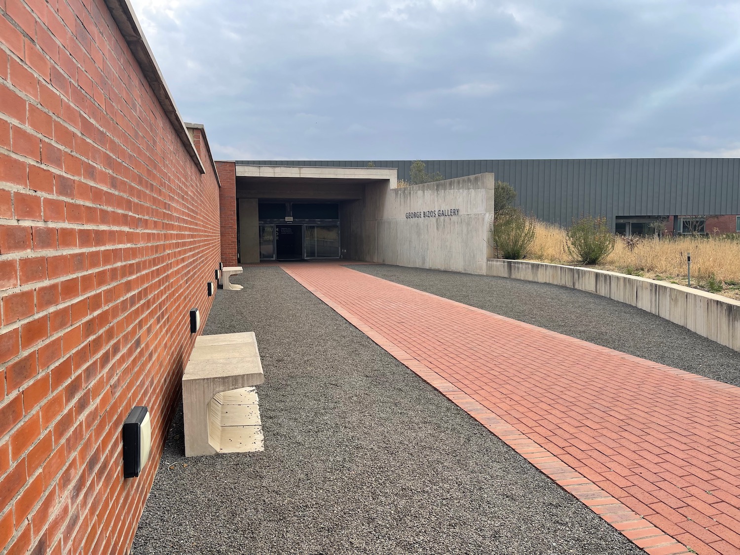 a brick walkway with a bench in front of a building