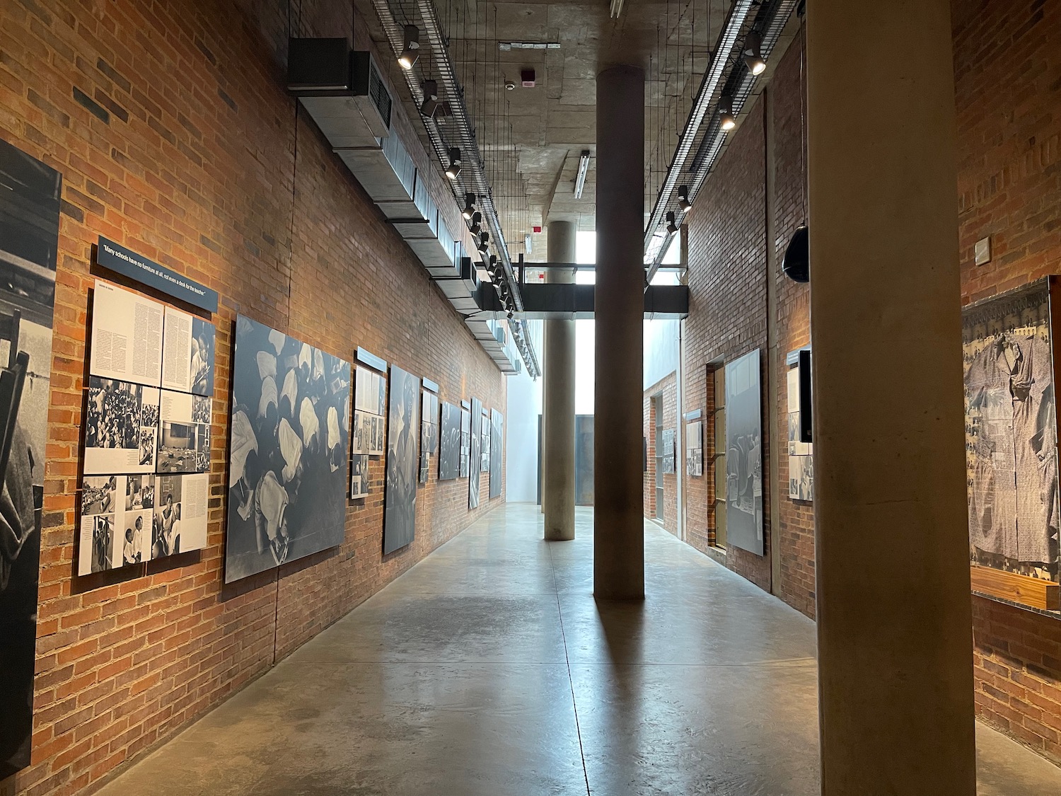 a long brick hallway with pictures on the wall