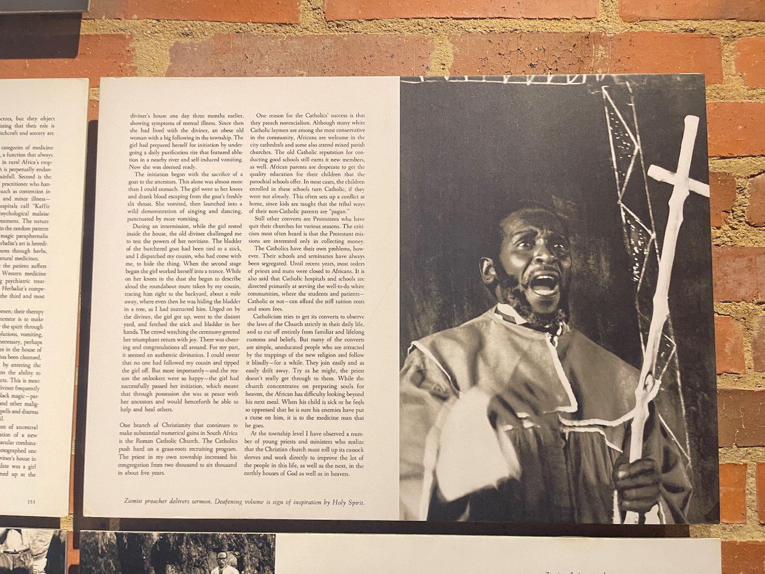 a black man holding a stick and a newspaper on a brick wall