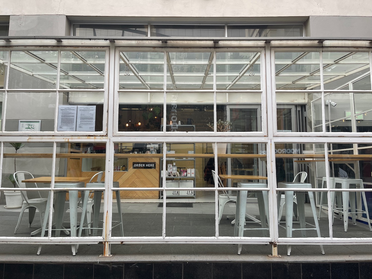 a glass wall with tables and chairs outside