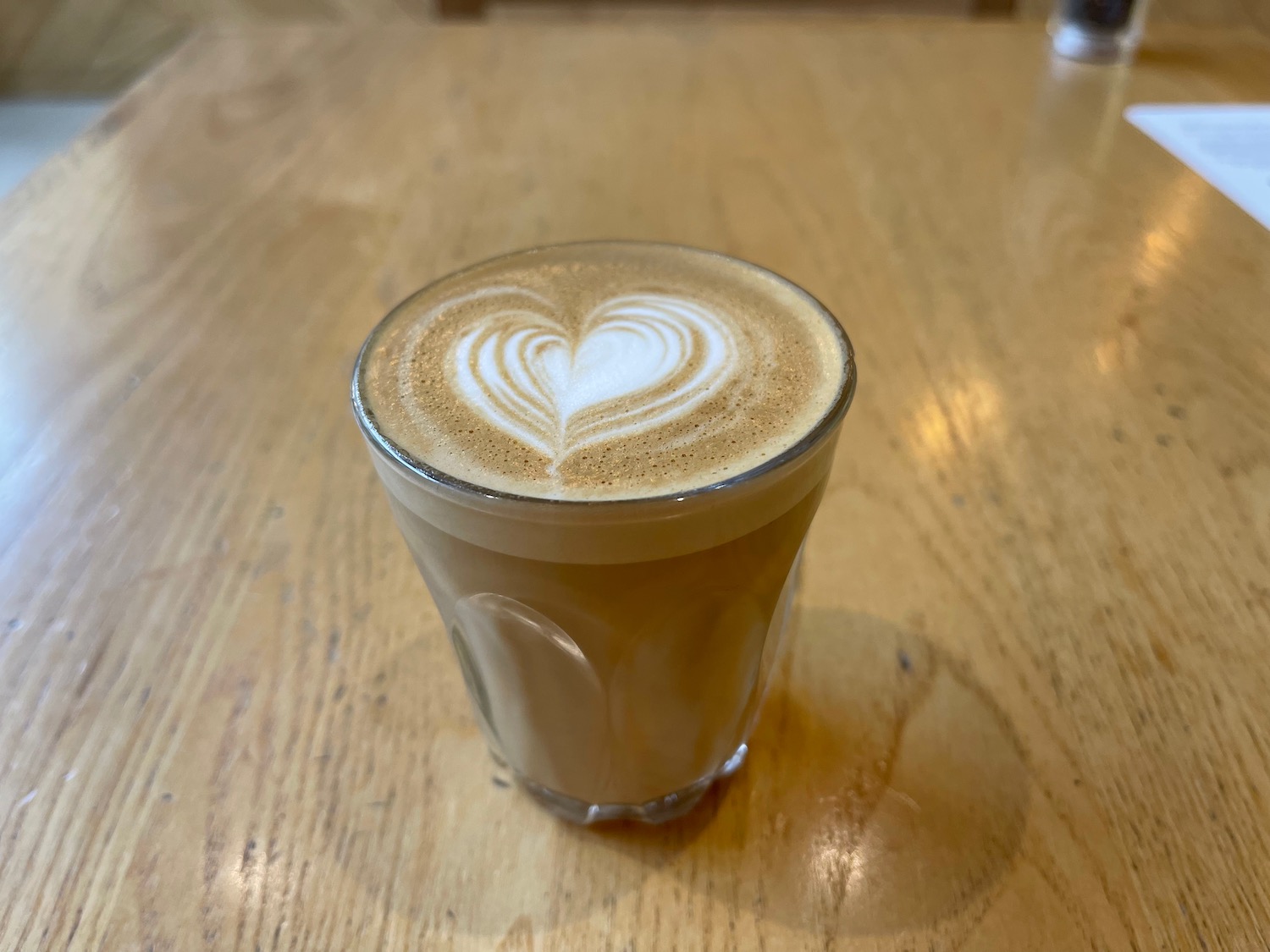 a glass of coffee with a heart shaped foam in it